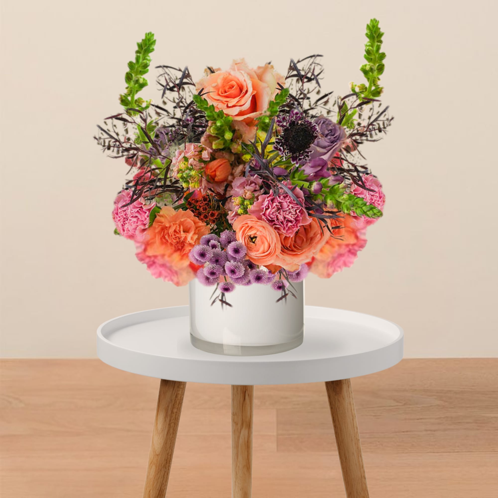 Colorful bouquet of pink, peach, and purple flowers in a clear glass vase