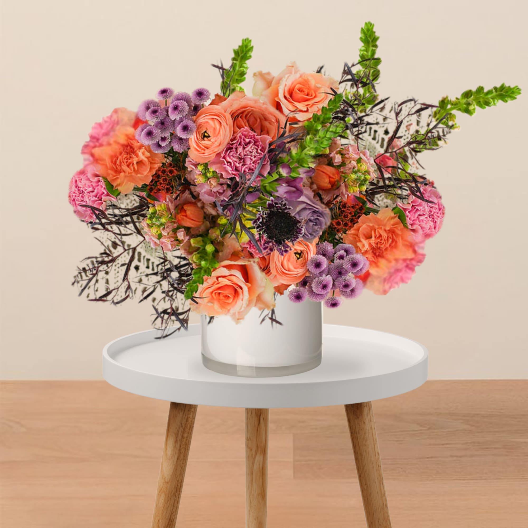 Colorful bouquet of coral, pink, and purple flowers in a white vase