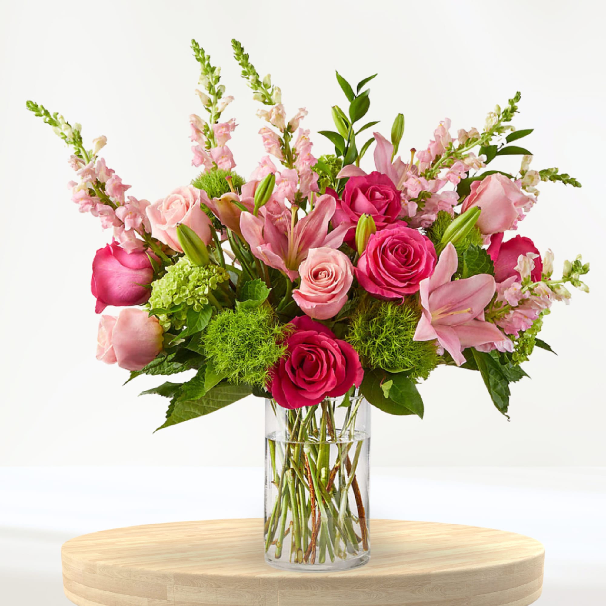 Pink roses and lilies arranged in a clear glass vase