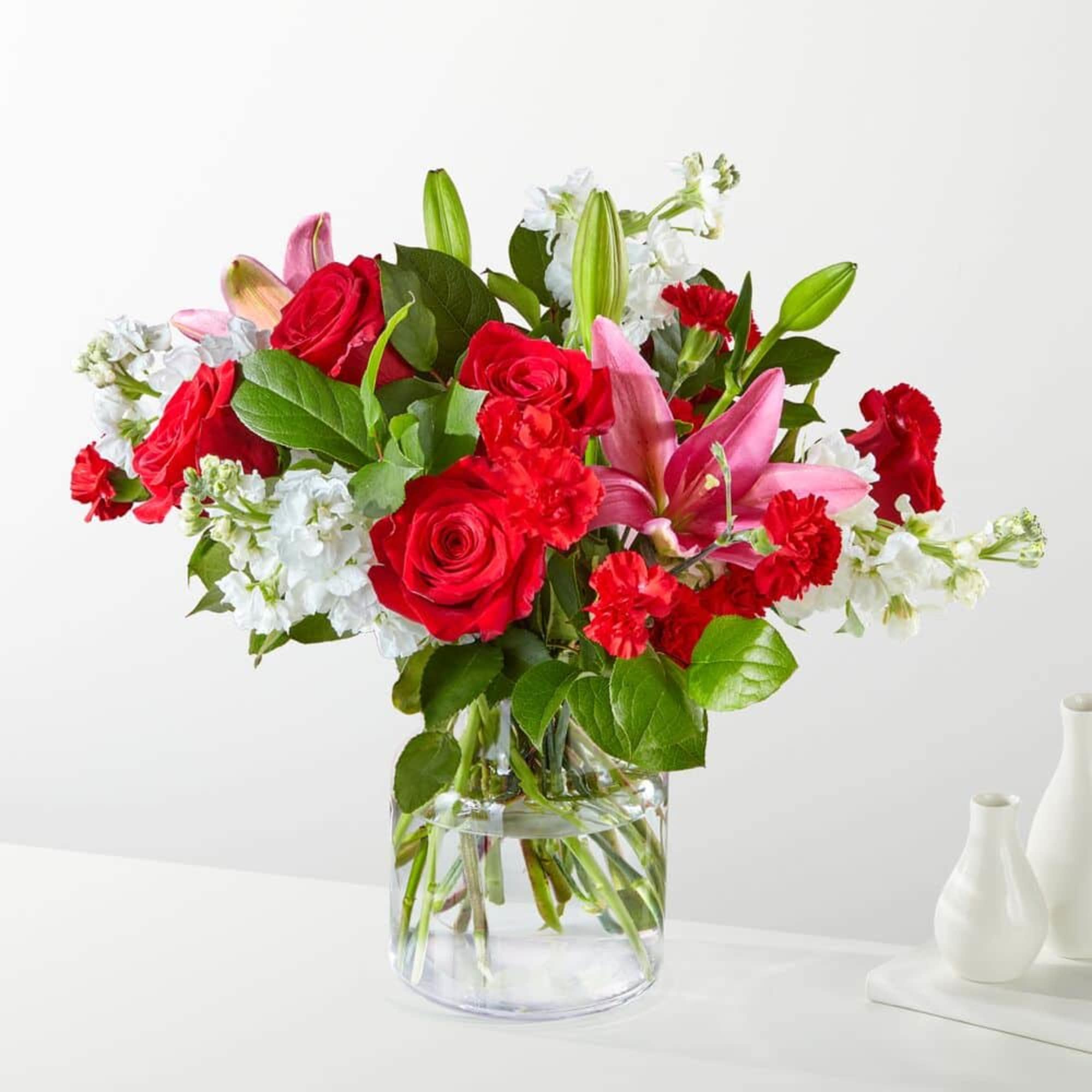Red roses and pink lilies in a clear glass vase