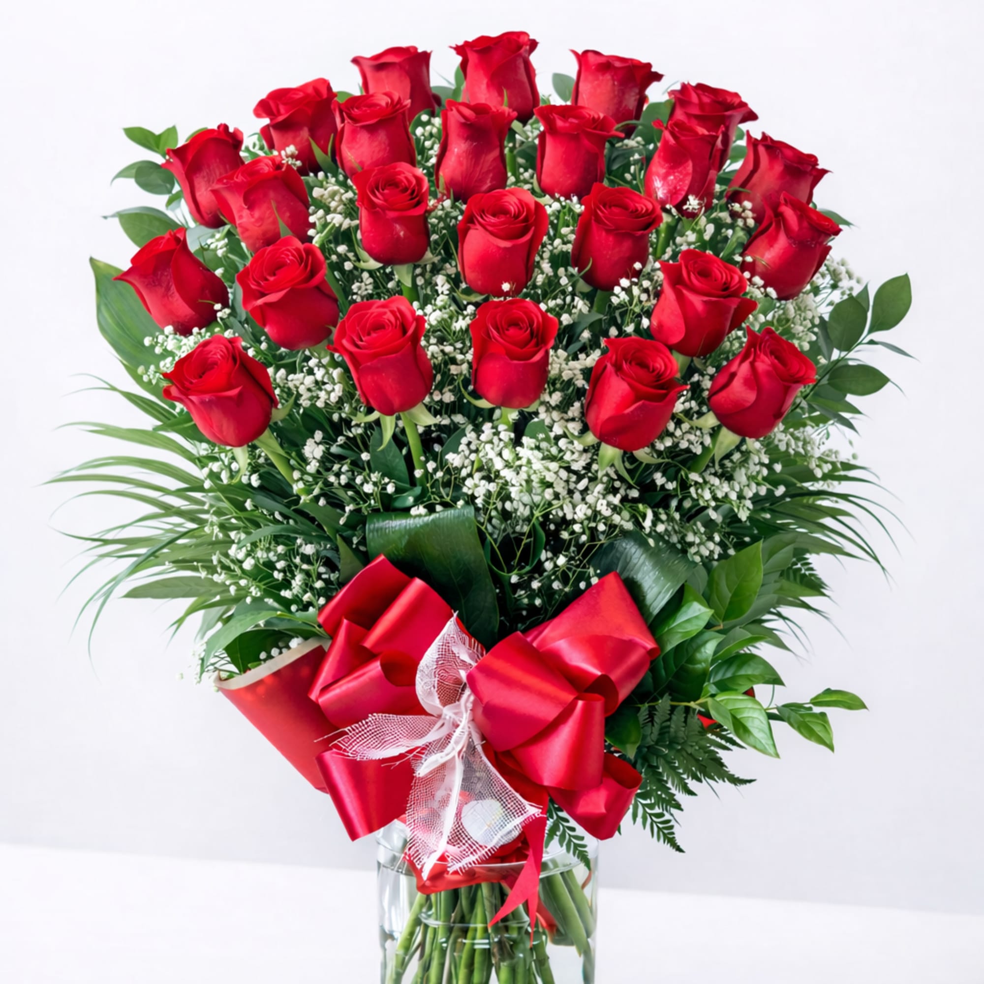 Bouquet of red roses in a clear glass vase with a red ribbon