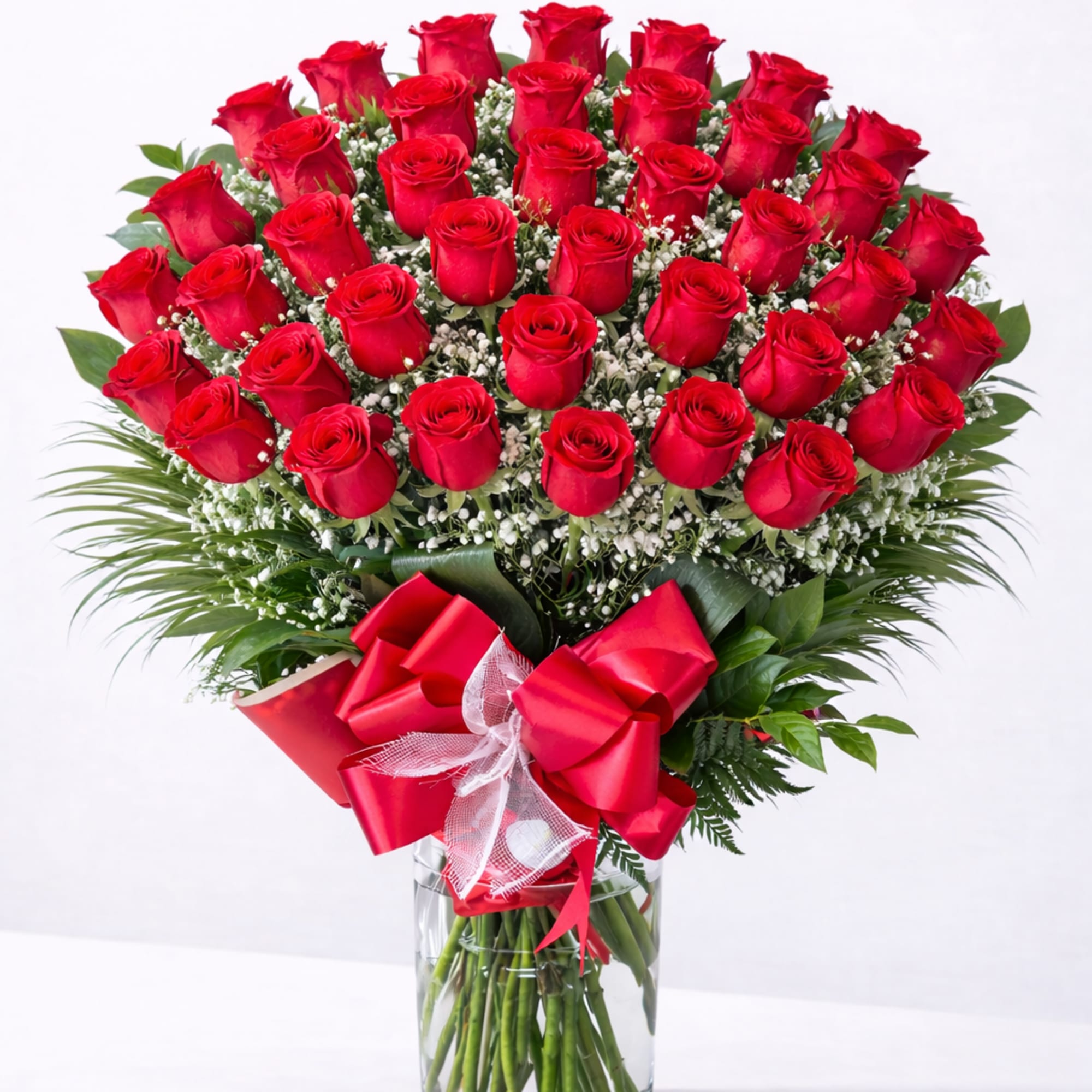 Bouquet of red roses in a clear glass vase with a red bow