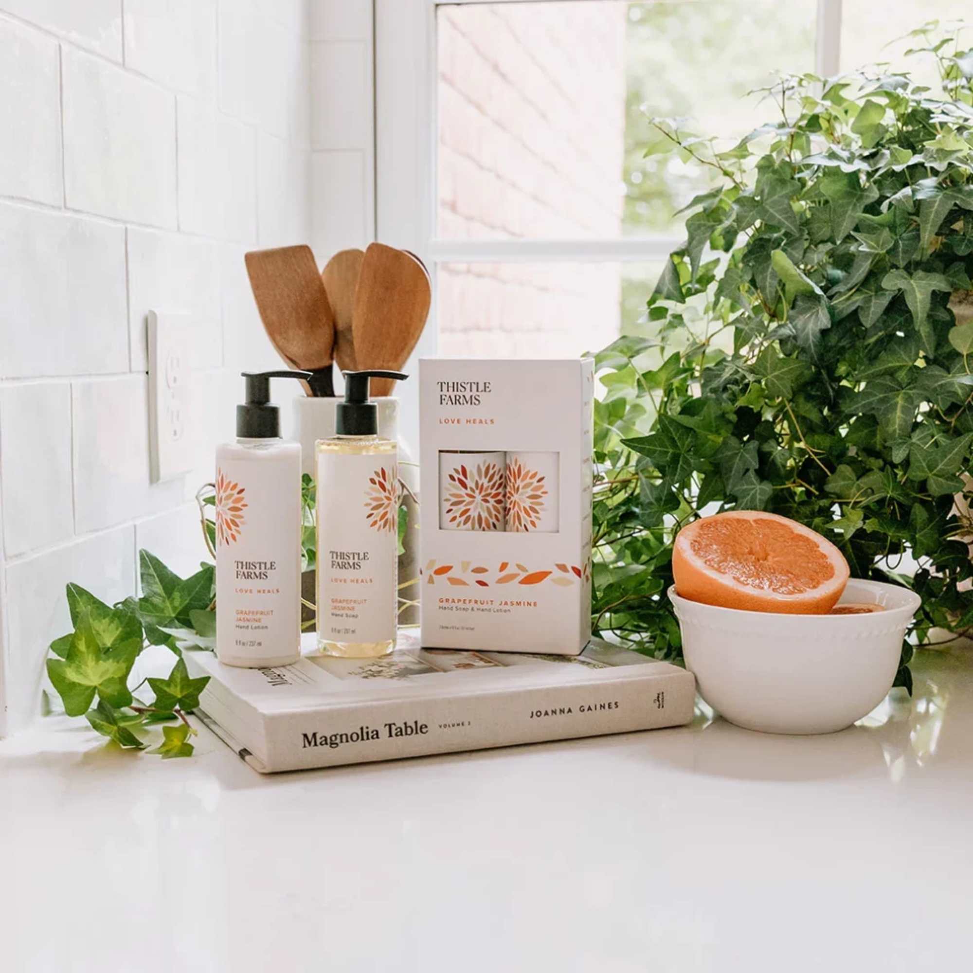 Gift set with soap bottles, a candle box, and a grapefruit in a bowl
