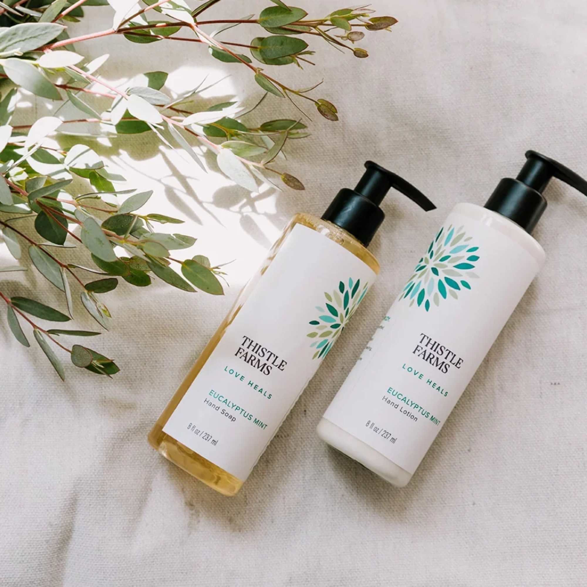 Two eucalyptus mint pump bottles on fabric with eucalyptus sprigs