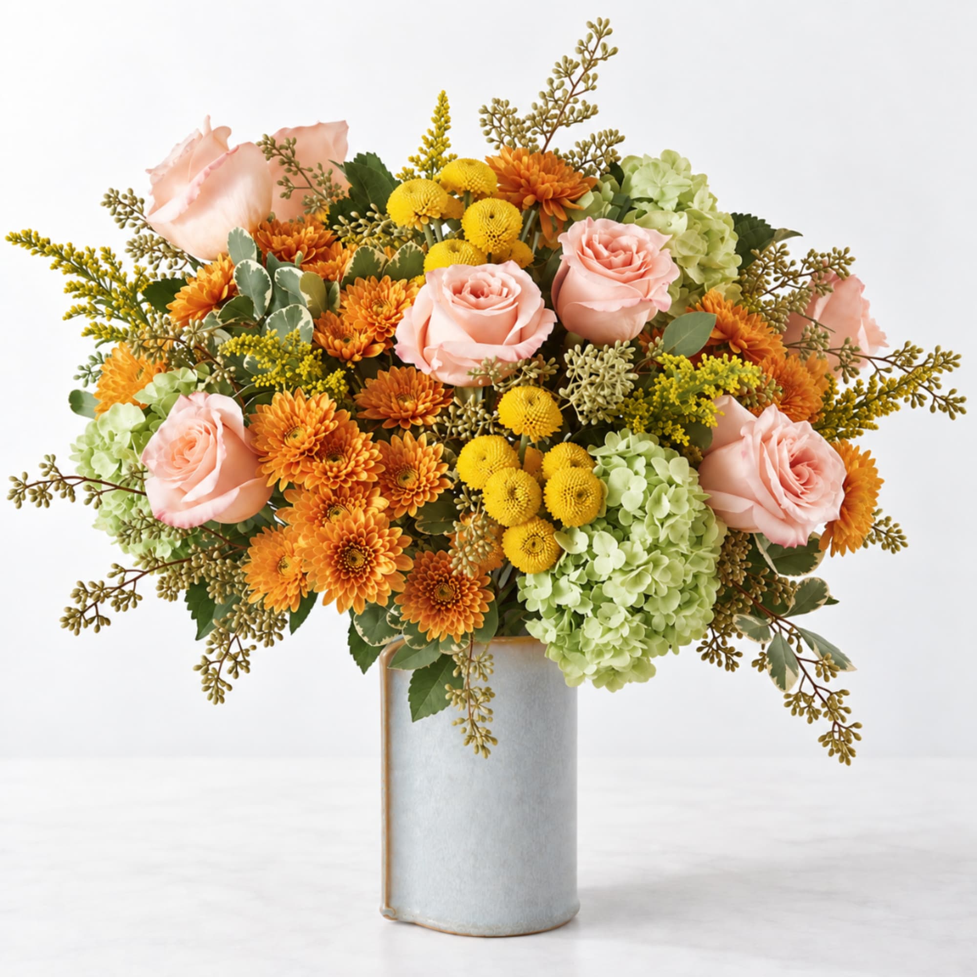 Bouquet of pink roses, orange mums, and yellow blooms in a ceramic vase