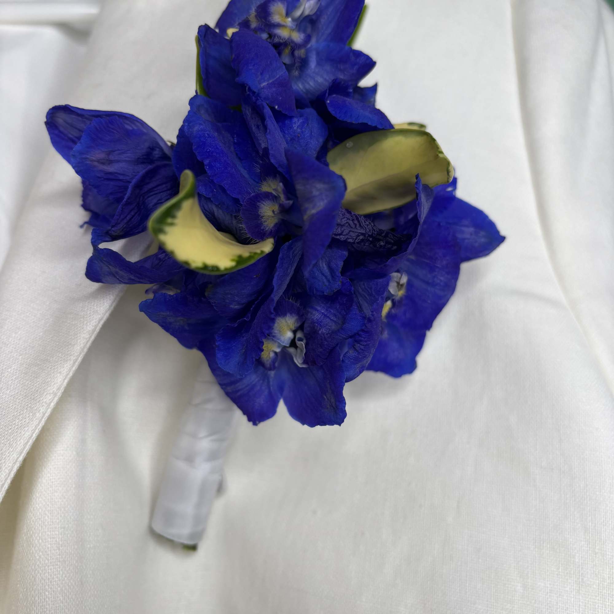 Blue flower boutonniere with white ribbon wrap
