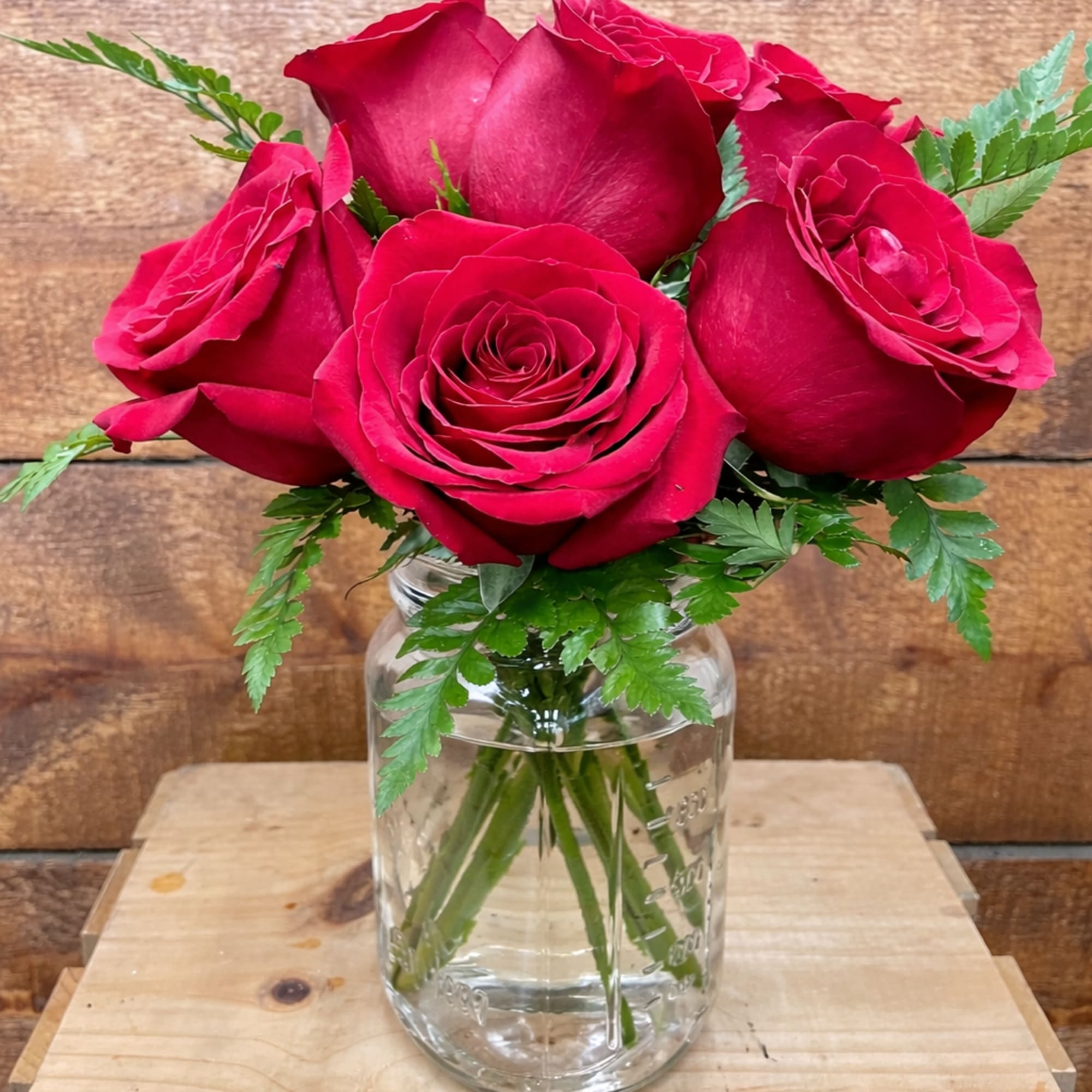 Red roses arranged in a clear glass jar vase, photo 2 of 4