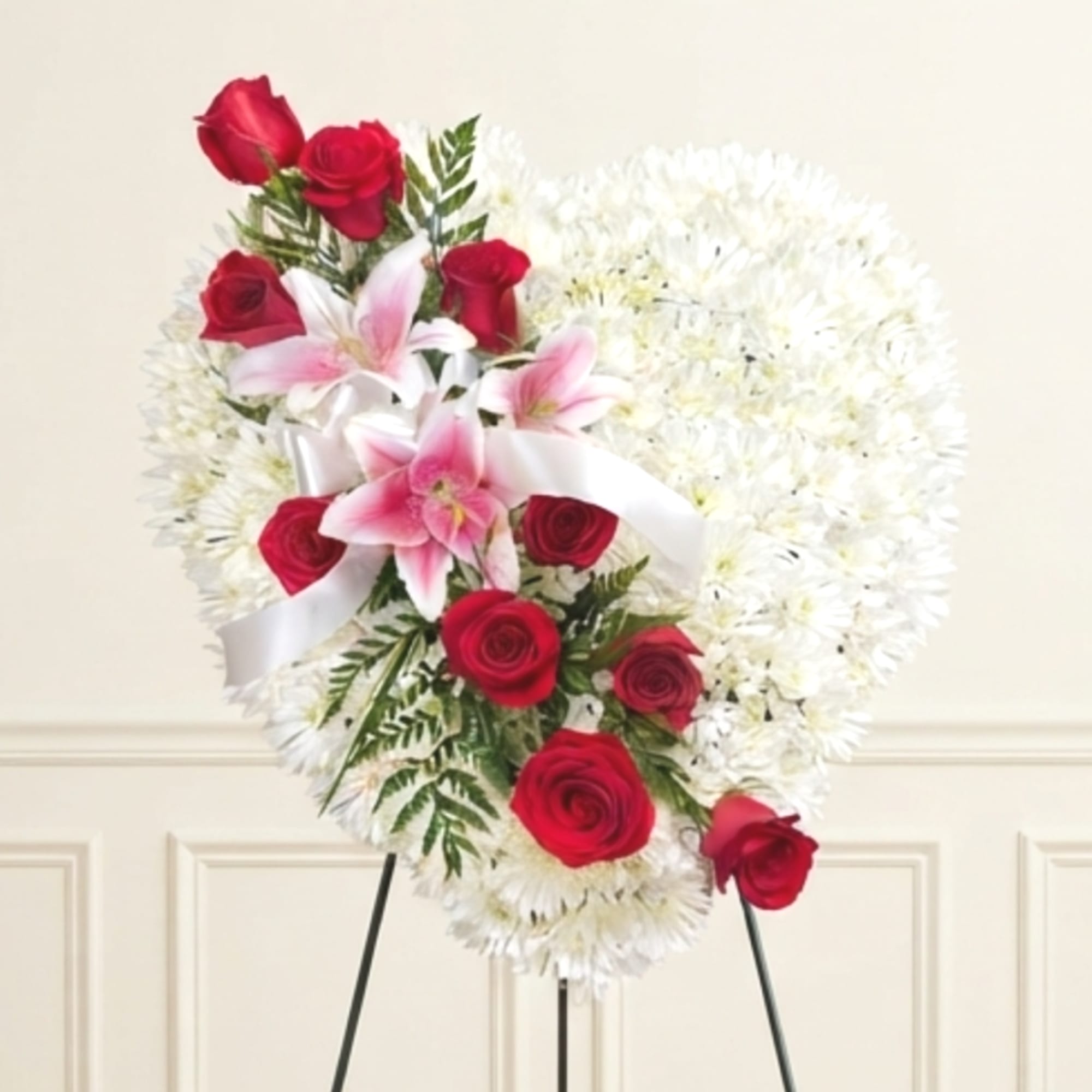 Heart-shaped floral spray with red roses and pink lilies on a stand