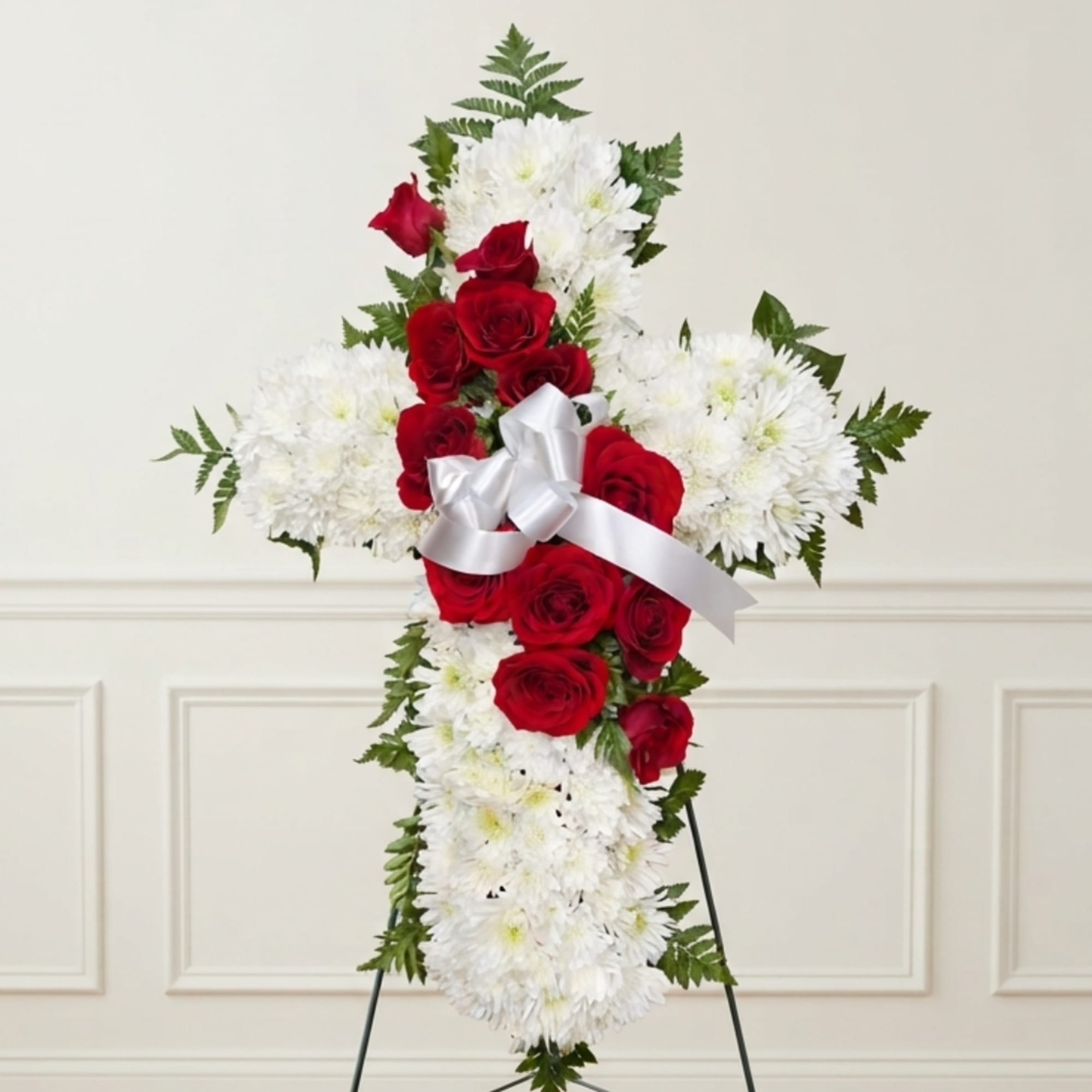 Cross-shaped floral arrangement of red roses and white chrysanthemums with a white ribbon