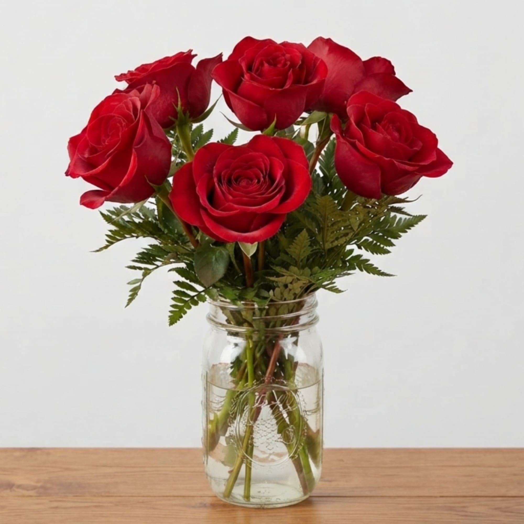 Red roses arranged in a clear glass jar vase