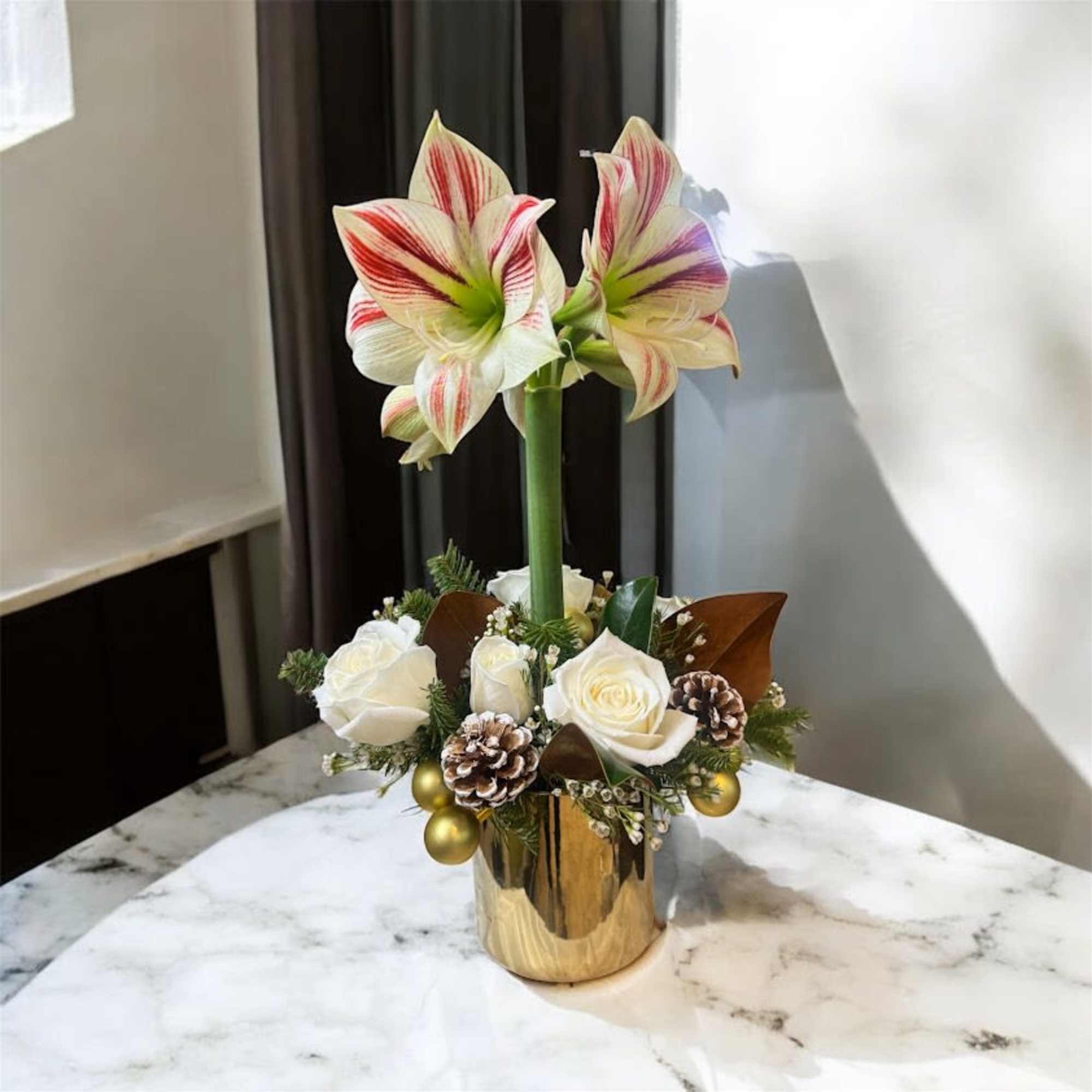 Amaryllis arrangement with white roses in a gold vase