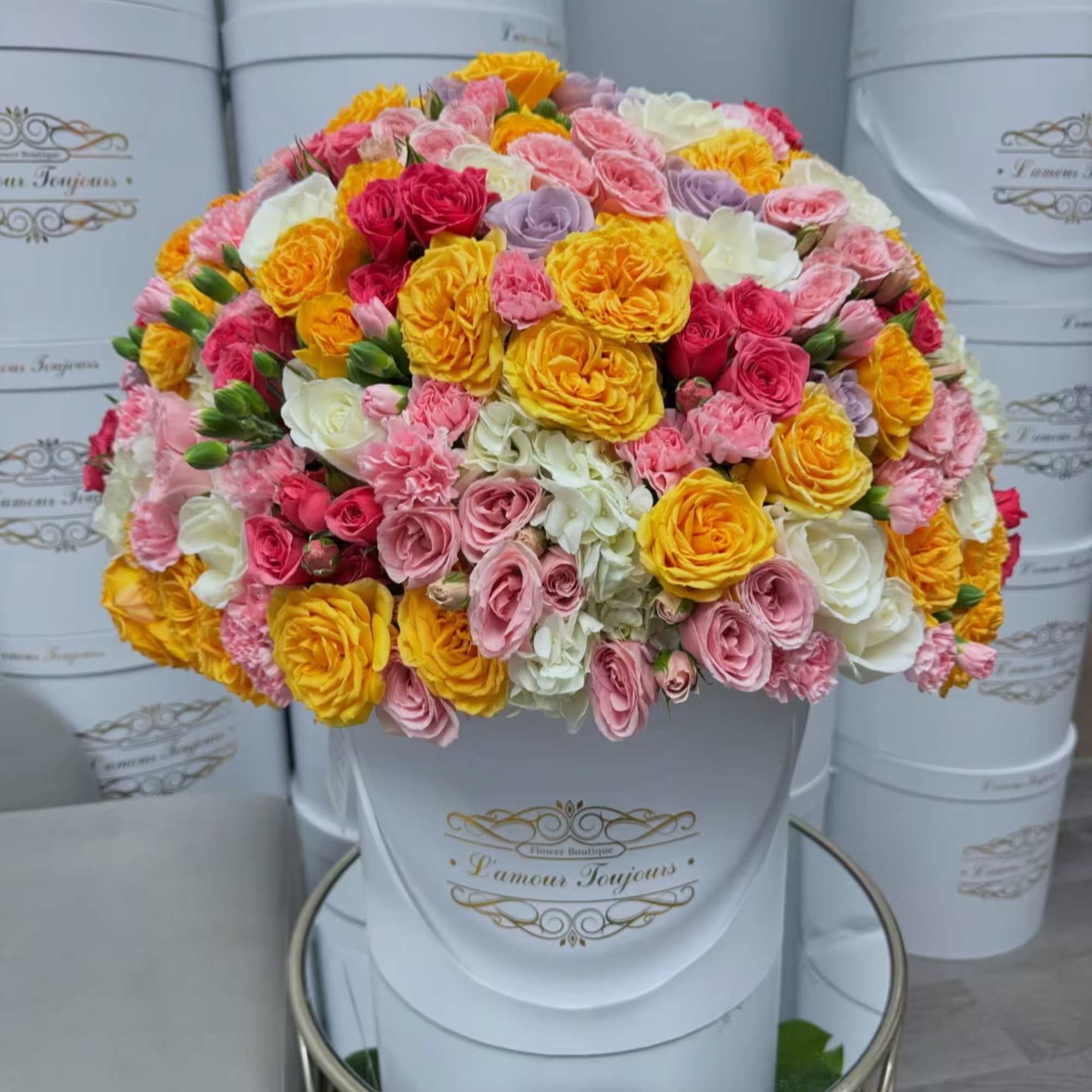 Bouquet of pink, yellow, white, and lavender roses in a white hat box