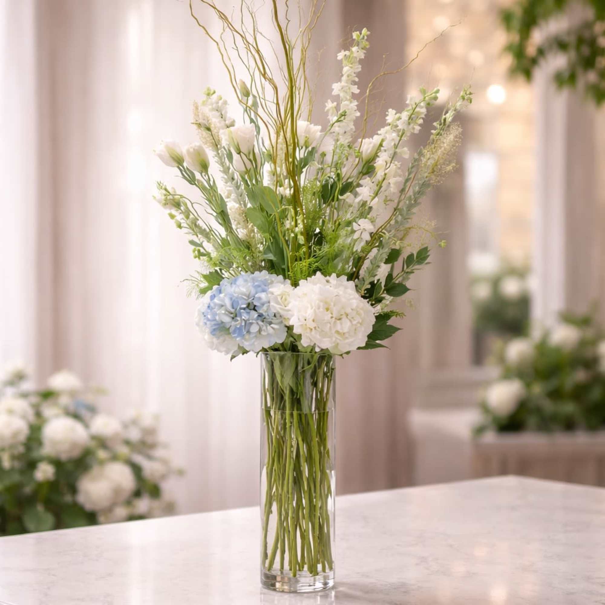 A graceful and elevated arrangement featuring soft white blooms, delicate seasonal florals
