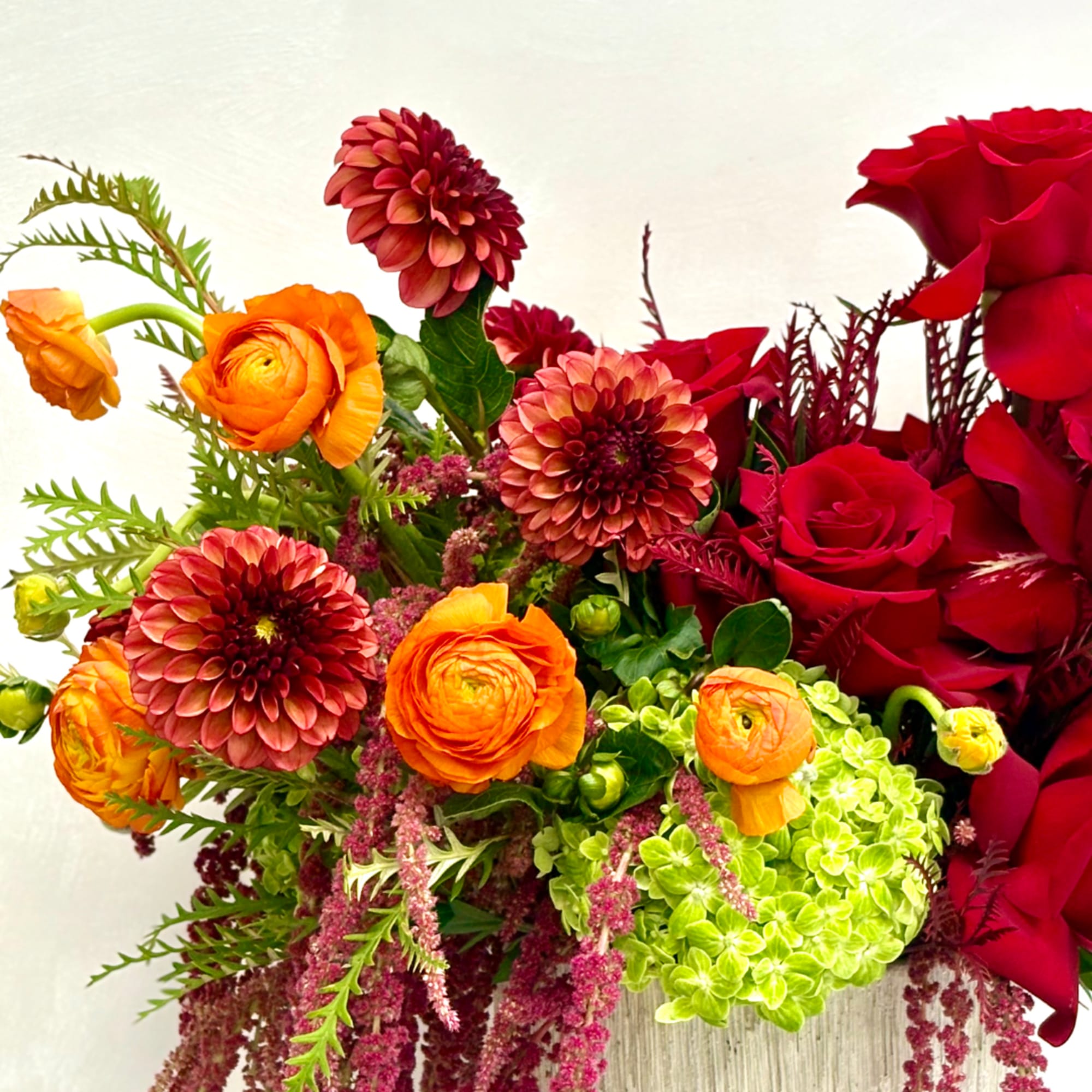 Bouquet of red roses, orange ranunculus, and green hydrangea