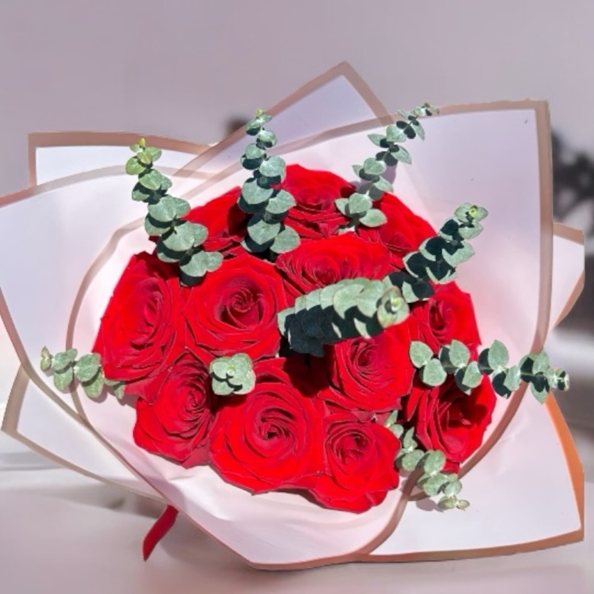 Bouquet of red roses with eucalyptus in white wrapping