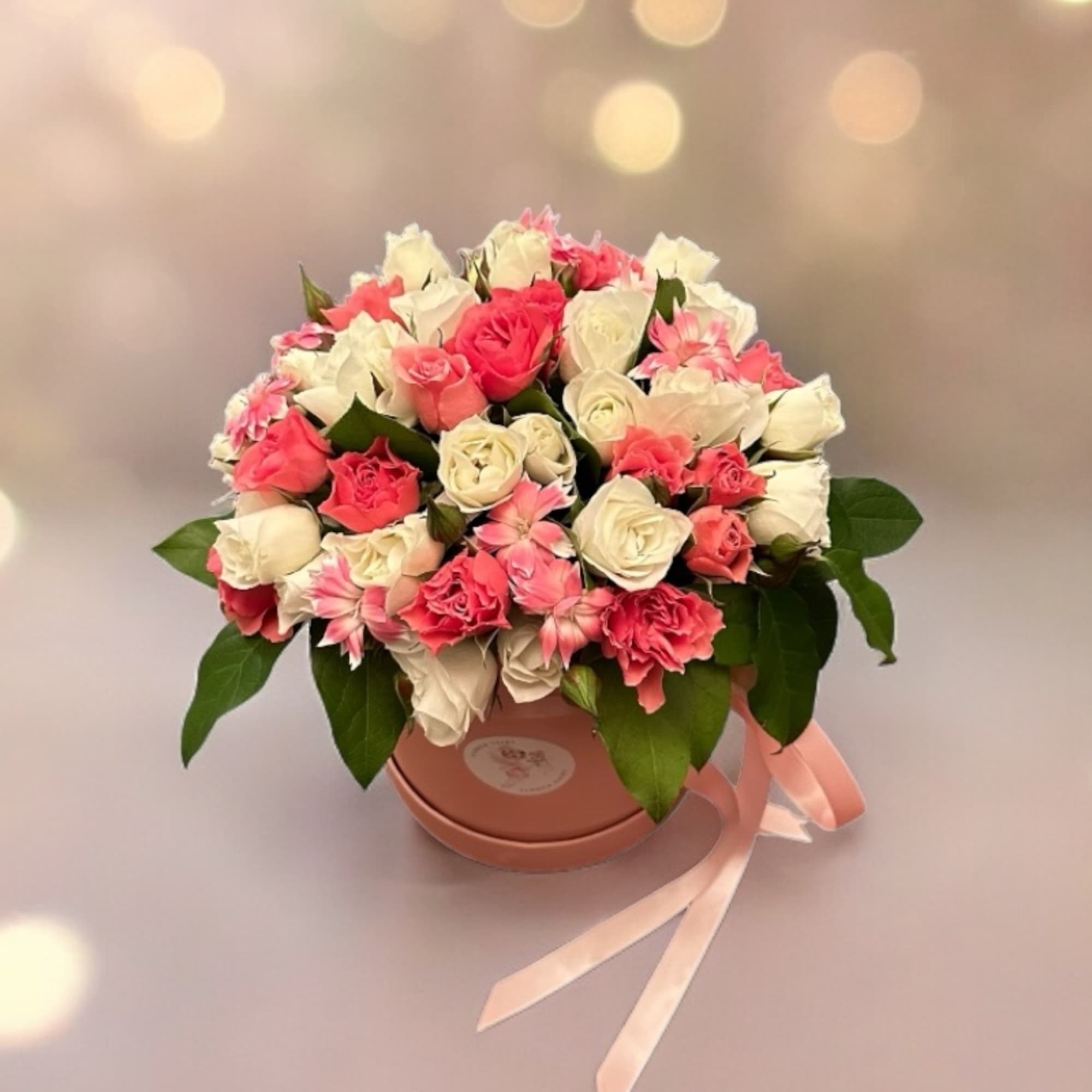 Pink and white rose bouquet in a round box with a ribbon