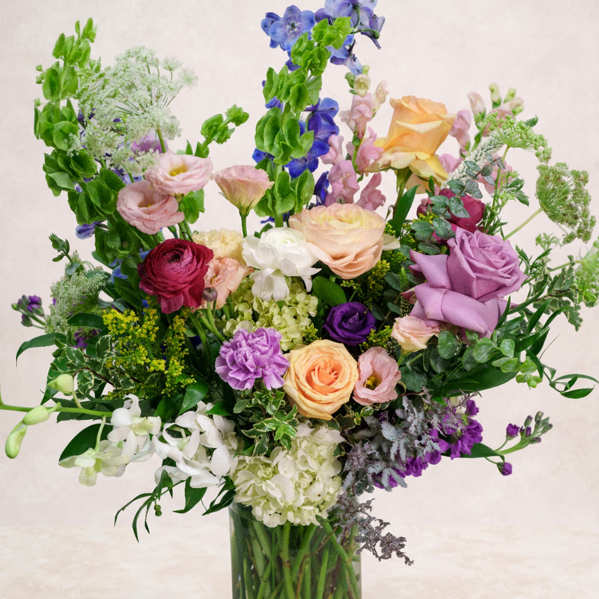 Mixed bouquet of roses, lisianthus, and hydrangeas in a glass vase