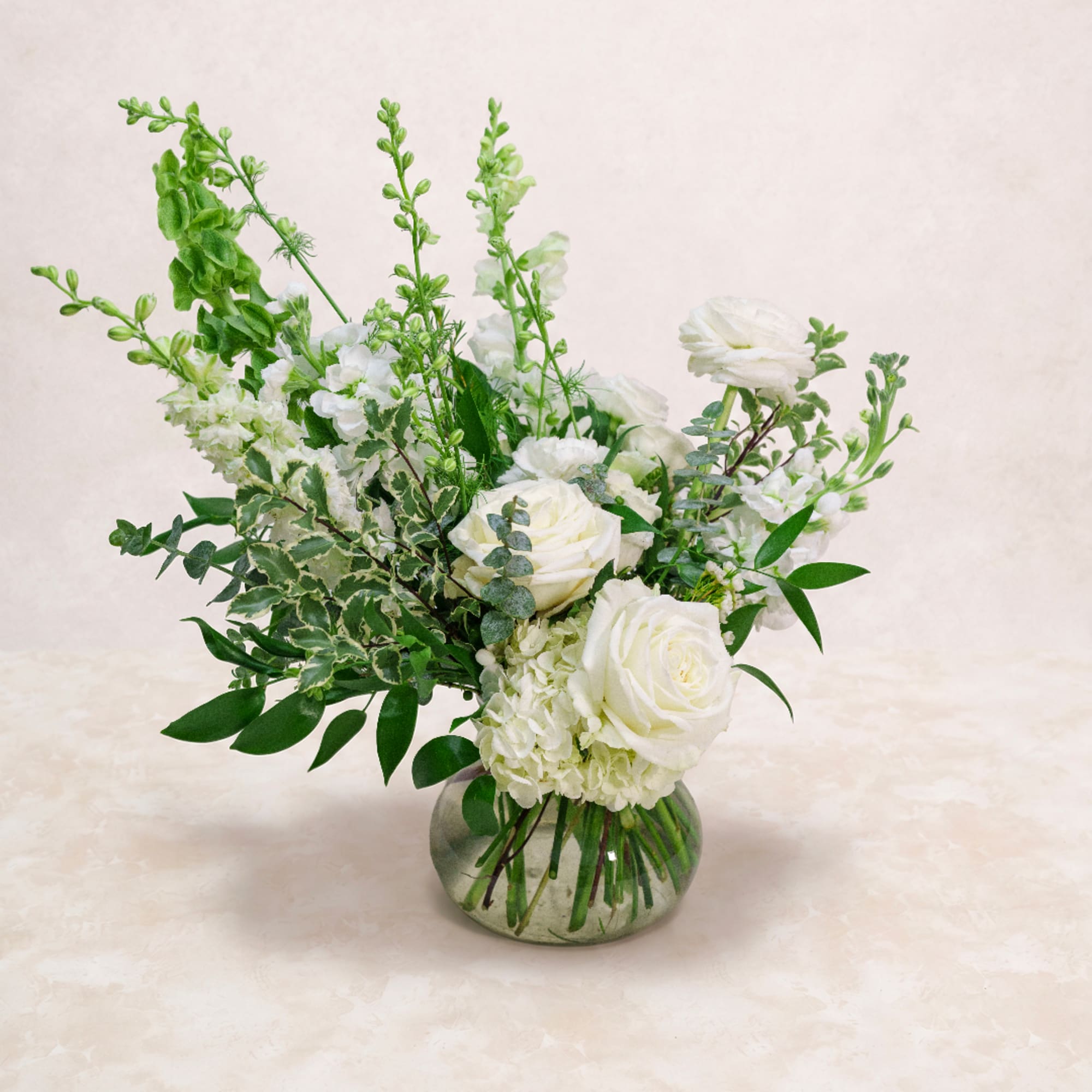 White roses and mixed white flowers in a round glass vase
