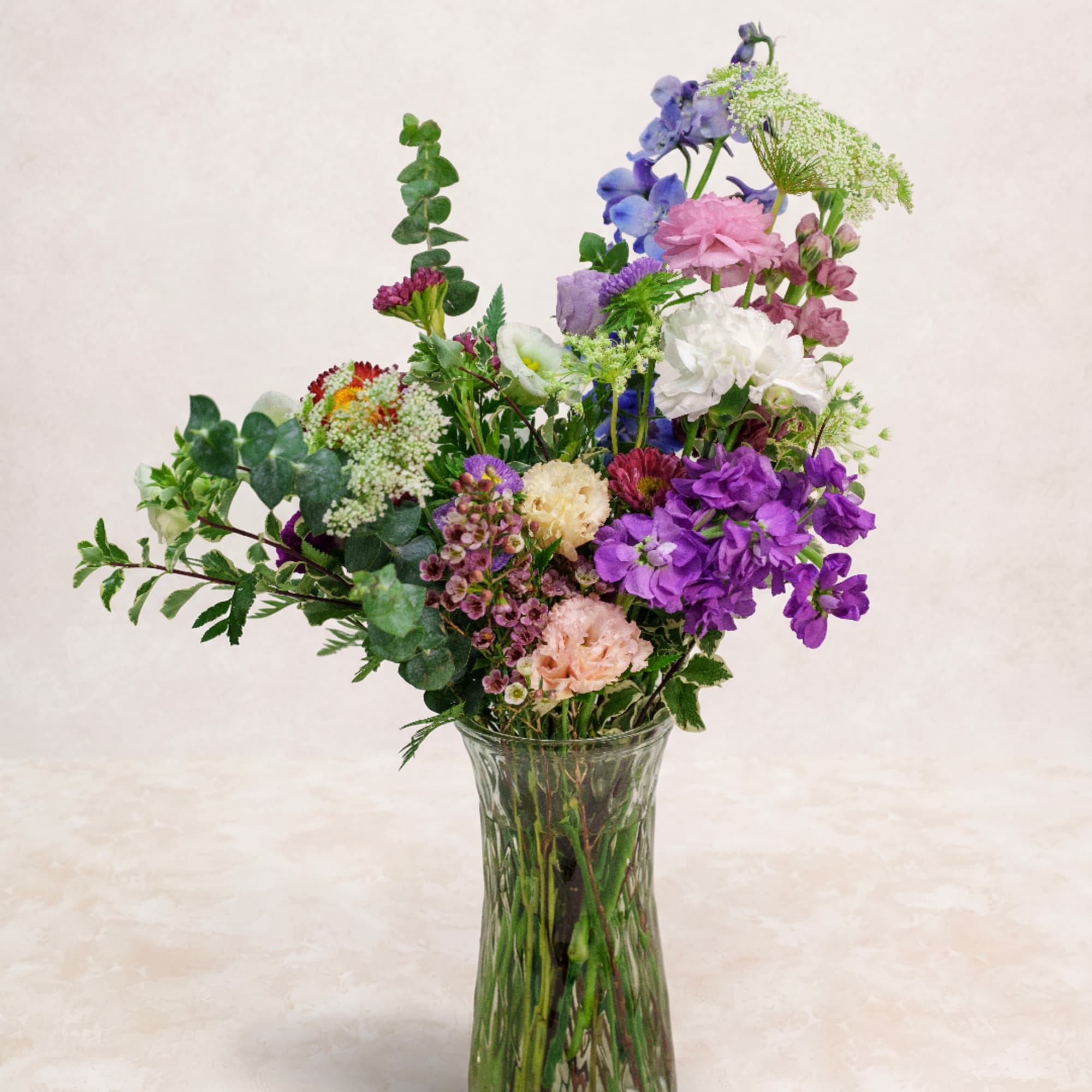 Mixed bouquet of purple, pink, and white flowers in a clear glass vase, photo 2 of 2