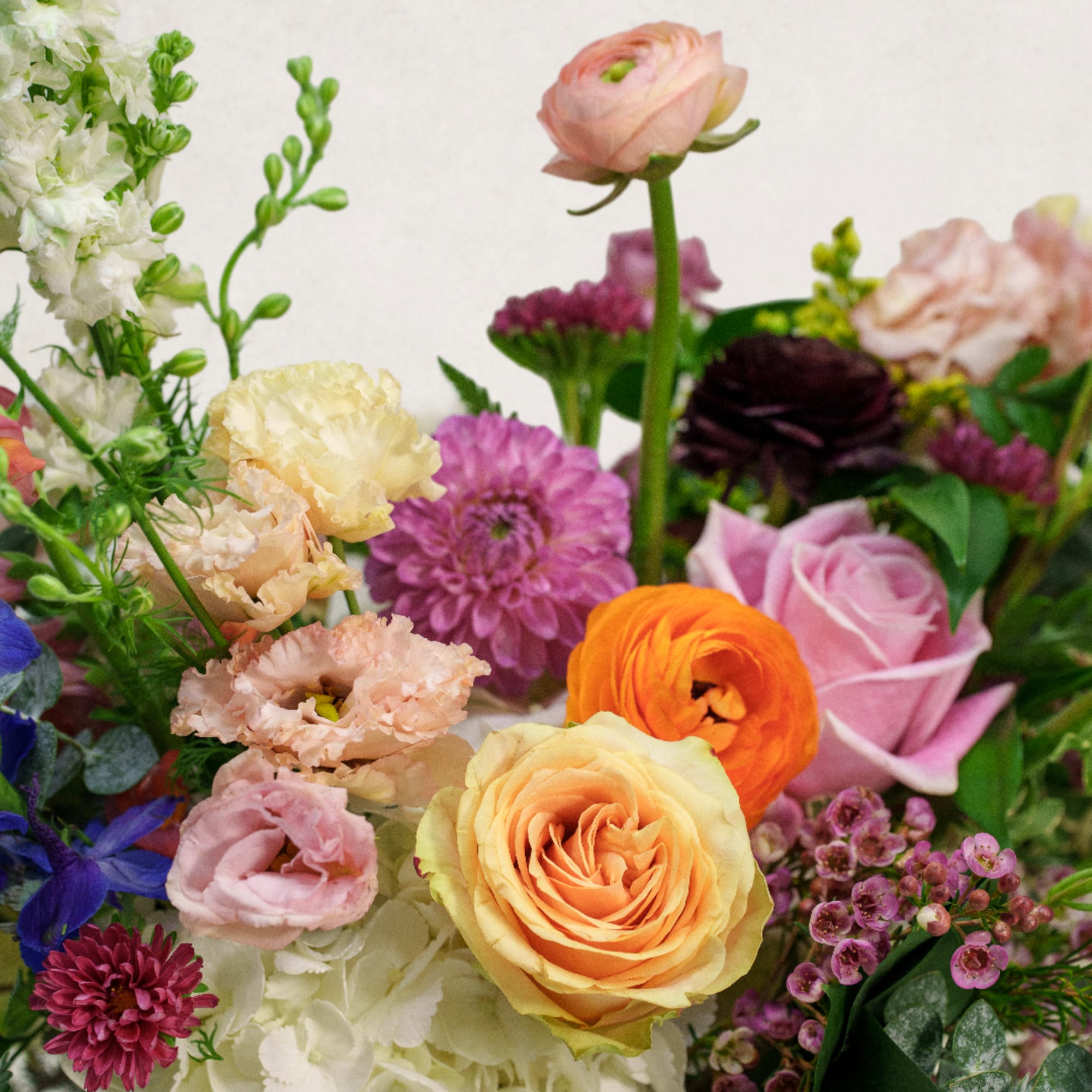 Mixed bouquet with roses, ranunculus, and carnations in pink, peach, and purple