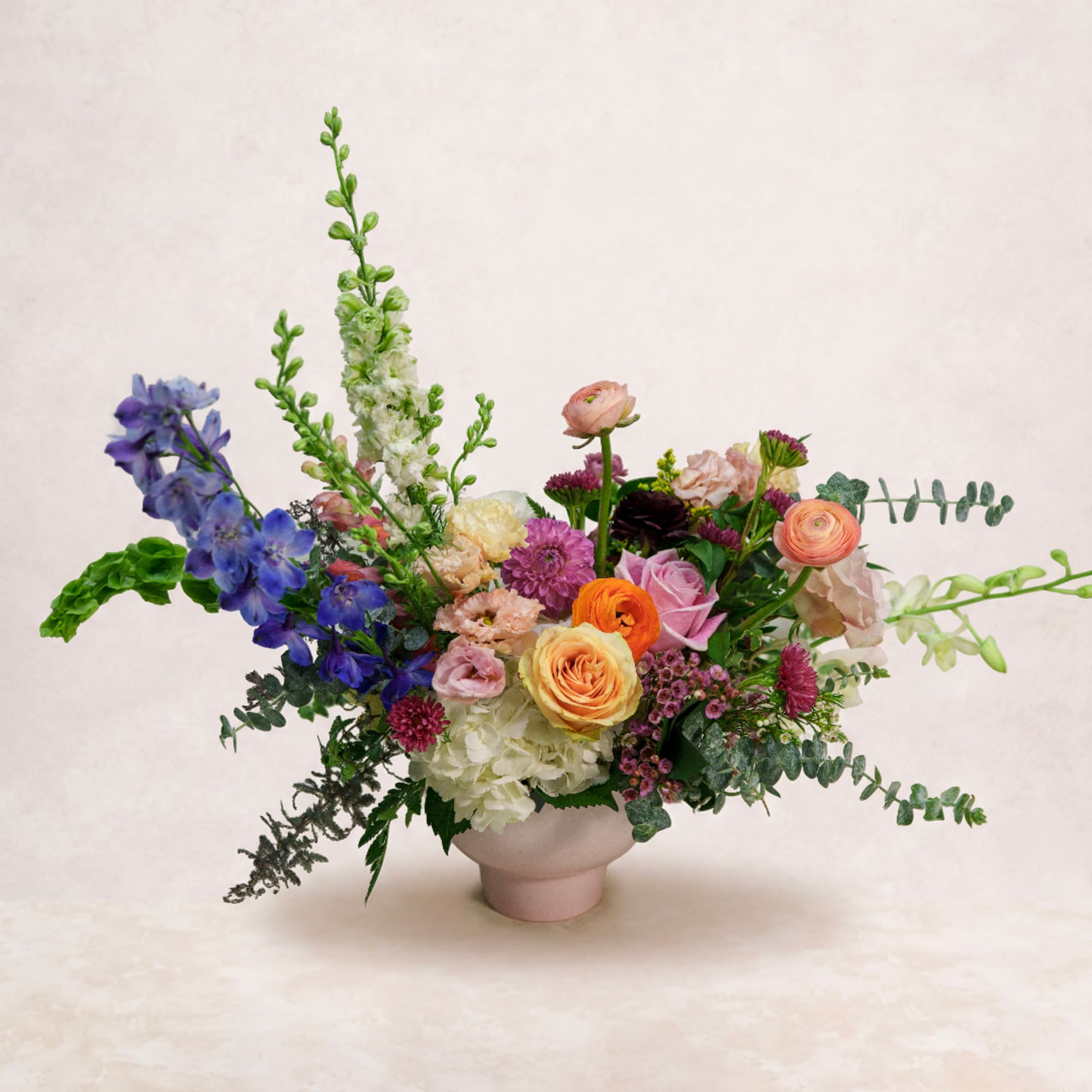 Colorful mixed flower arrangement in a pale pink vase