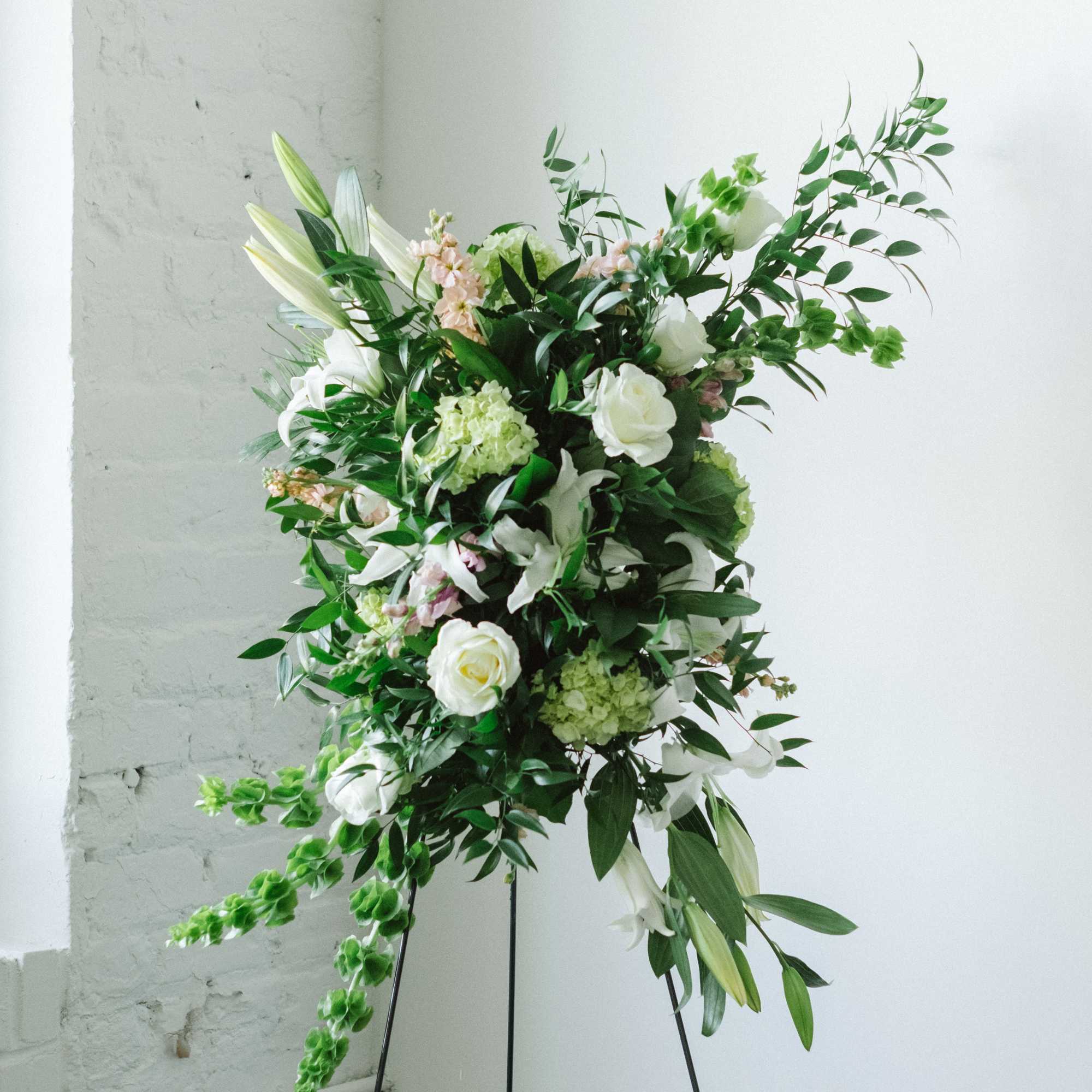 Tall white floral arrangement on a black stand