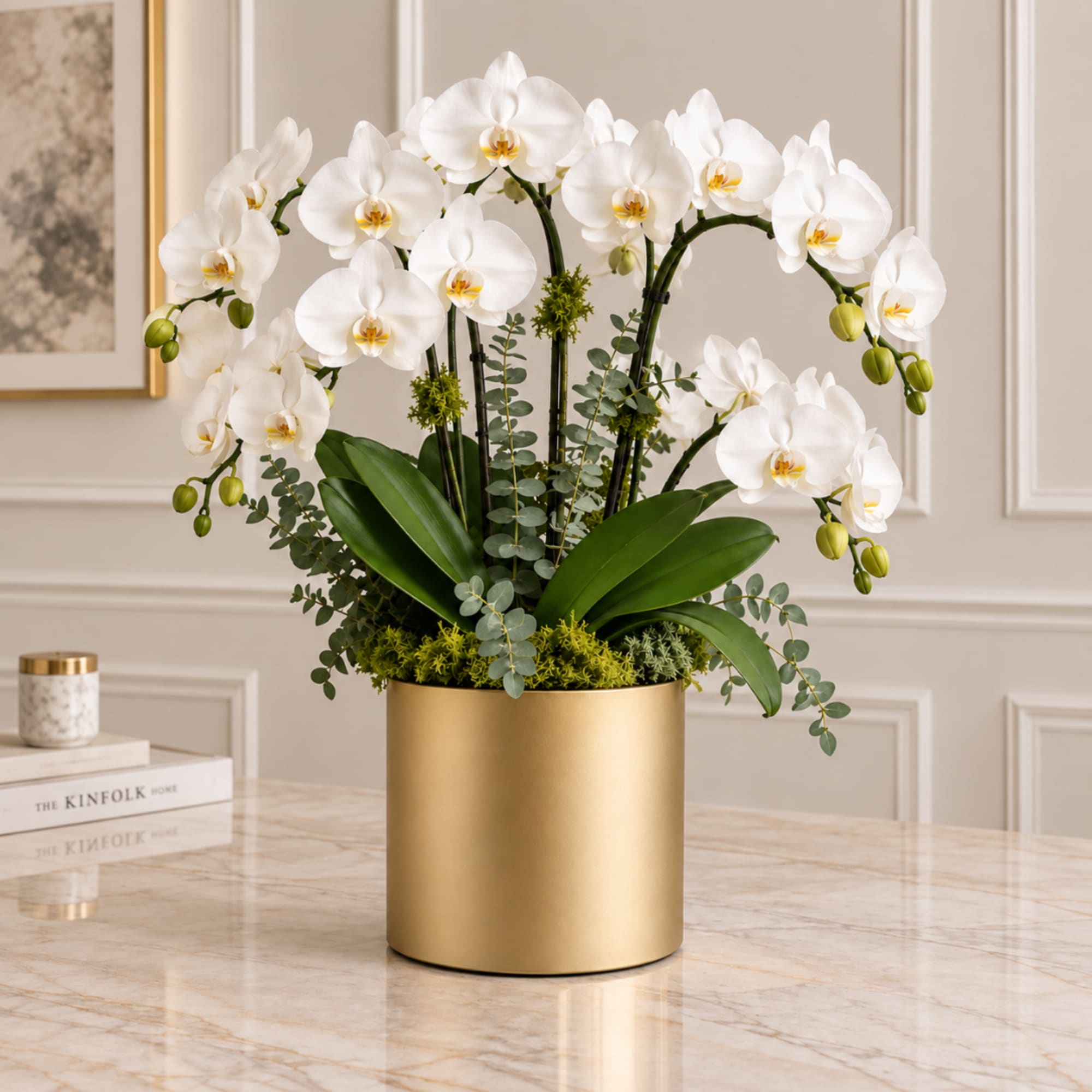 White orchids arranged in a gold cylindrical vase