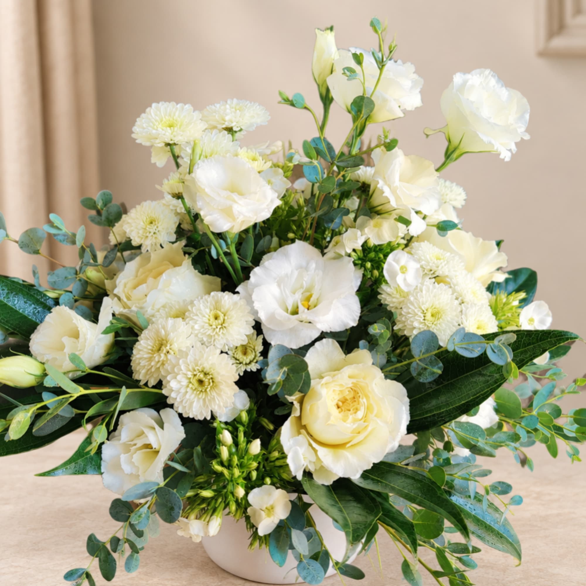 White floral arrangement in a low white vase with roses and mums