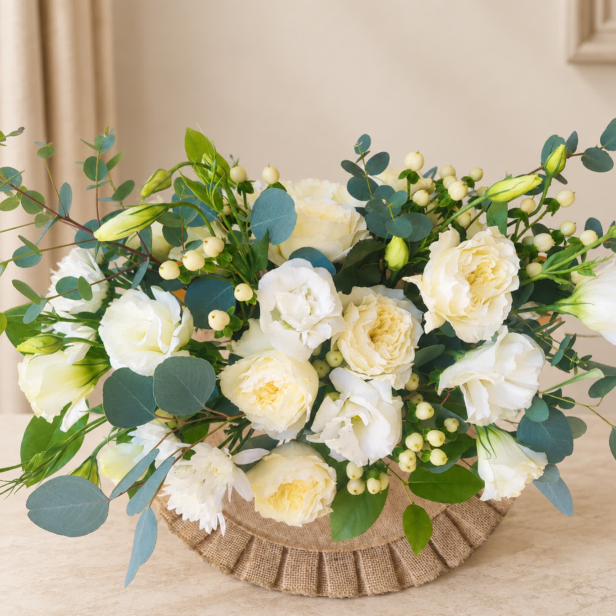 White roses and lisianthus in a burlap-wrapped arrangement