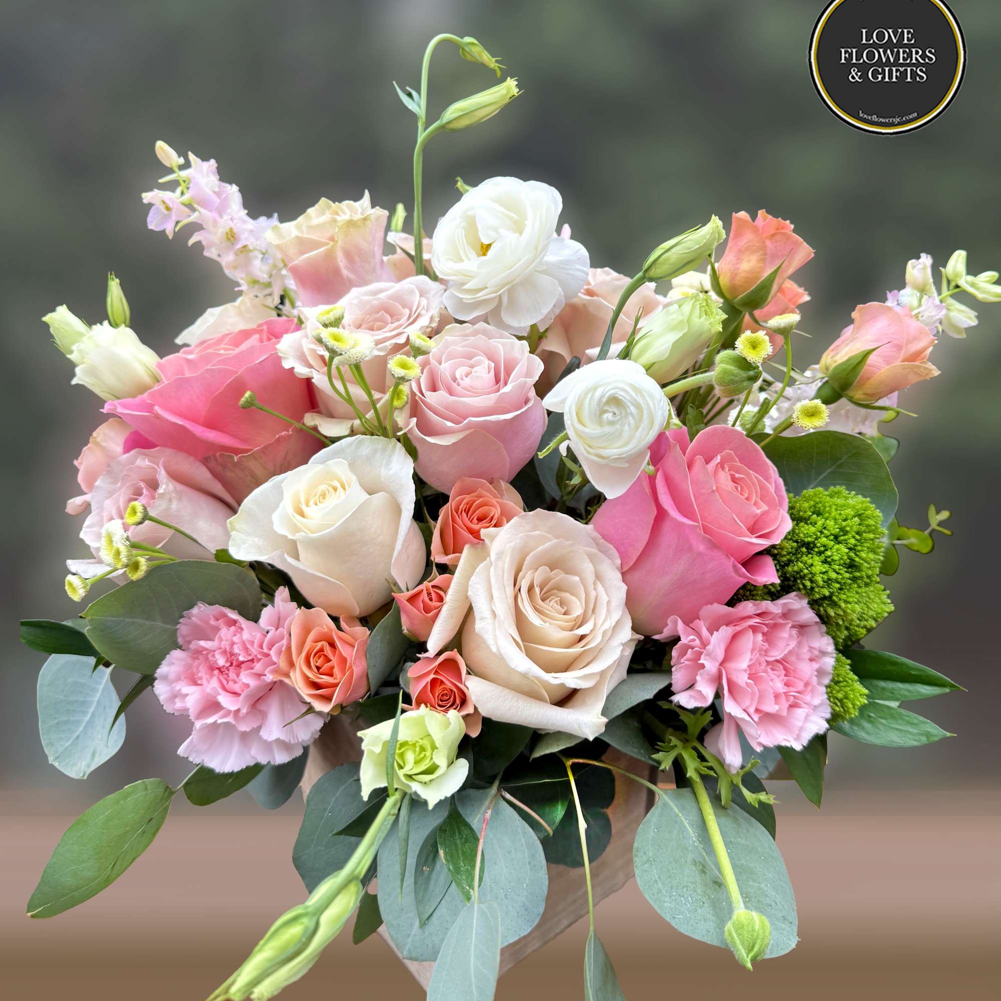 Mixed bouquet of pink and cream roses with carnations and lisianthus in a vase