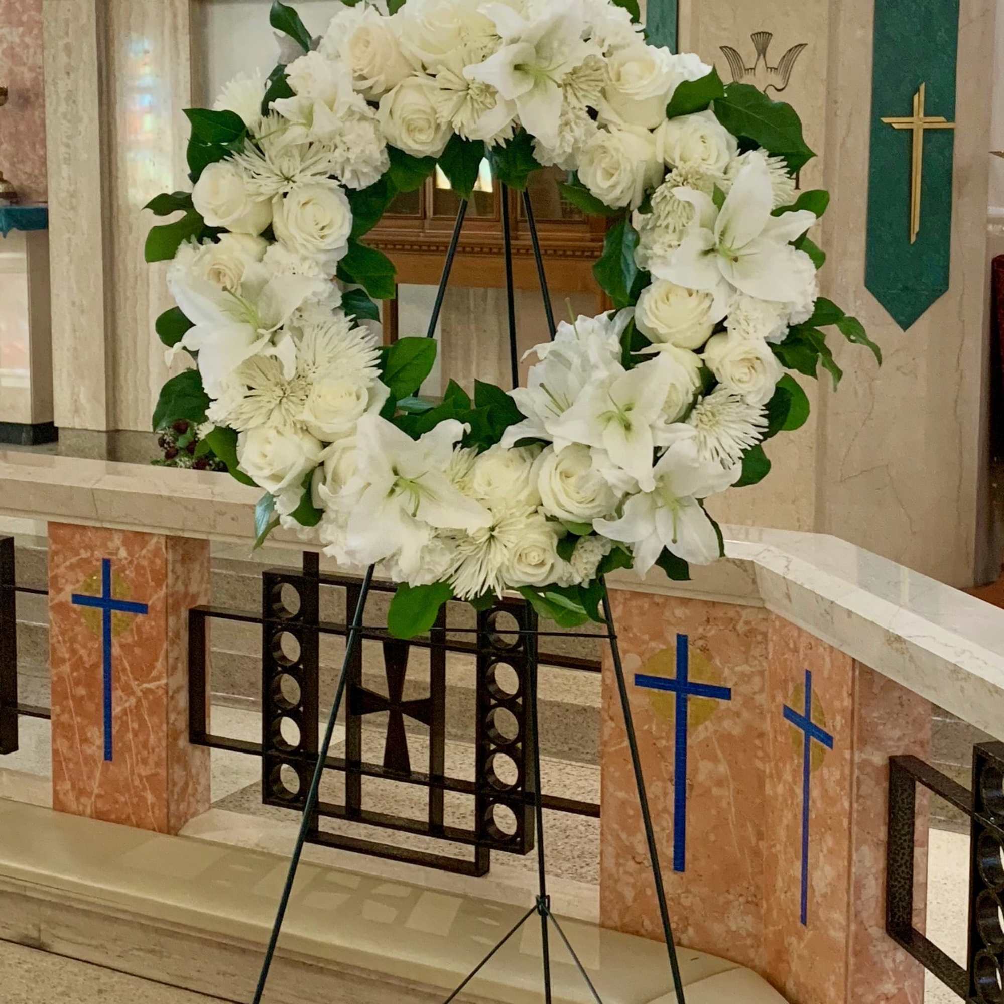 White floral wreath on a stand in a church interior