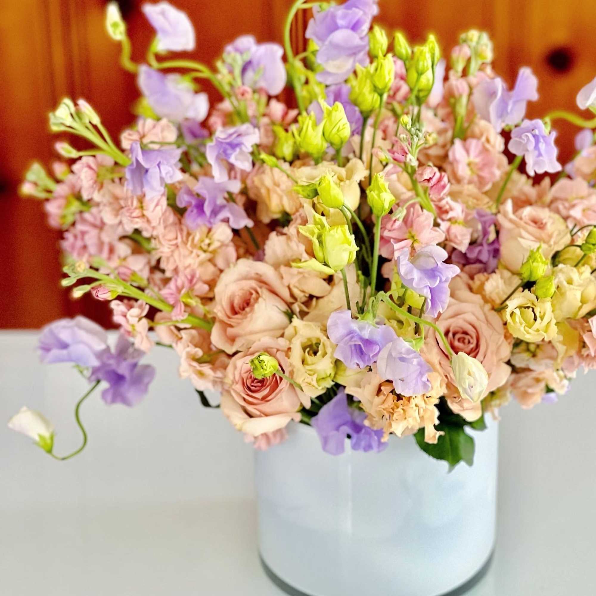 Pastel bouquet of roses, lisianthus, and carnations in a white vase