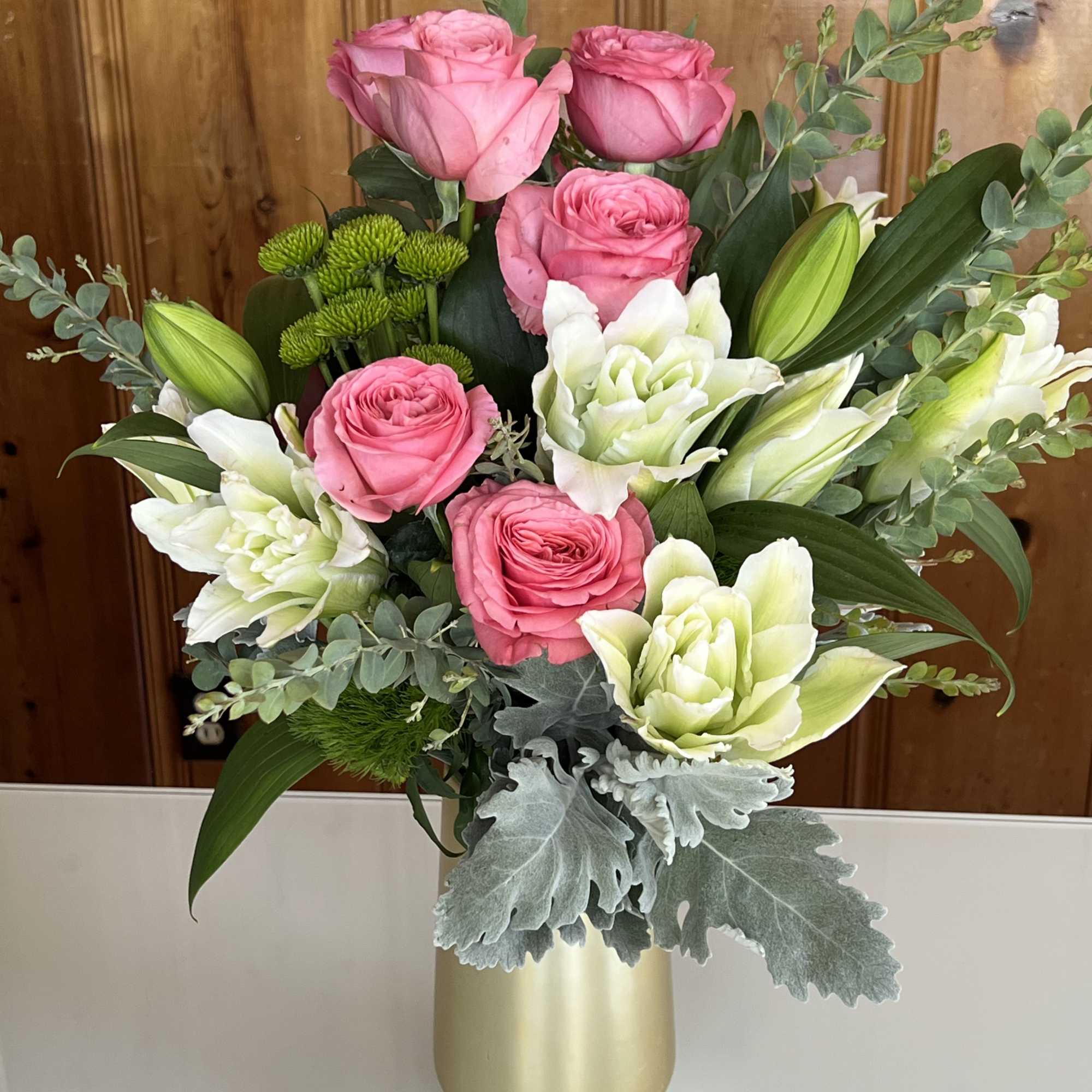 Pink roses and white lilies in a gold vase with silver foliage
