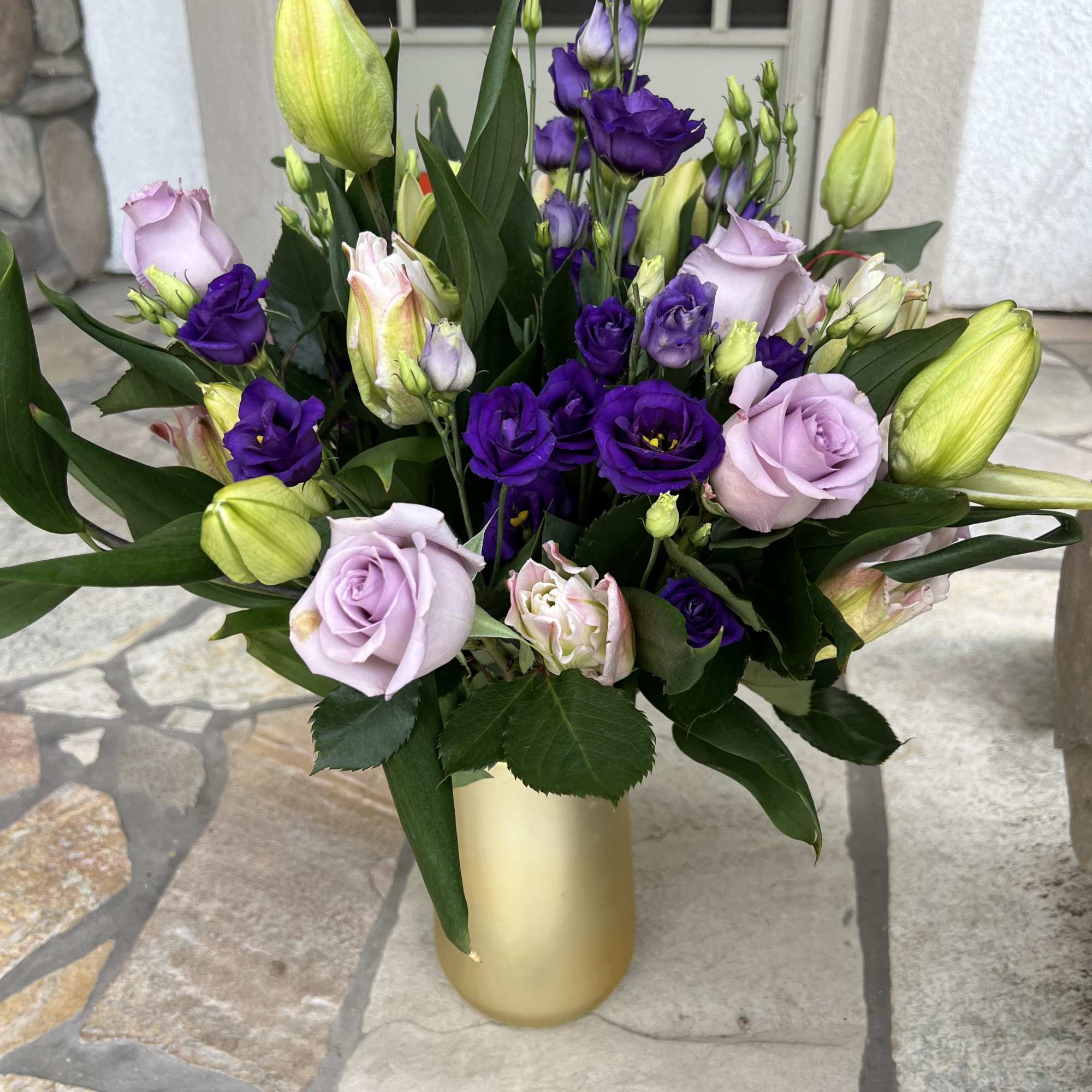 Bouquet of lavender roses and purple lisianthus in a gold vase