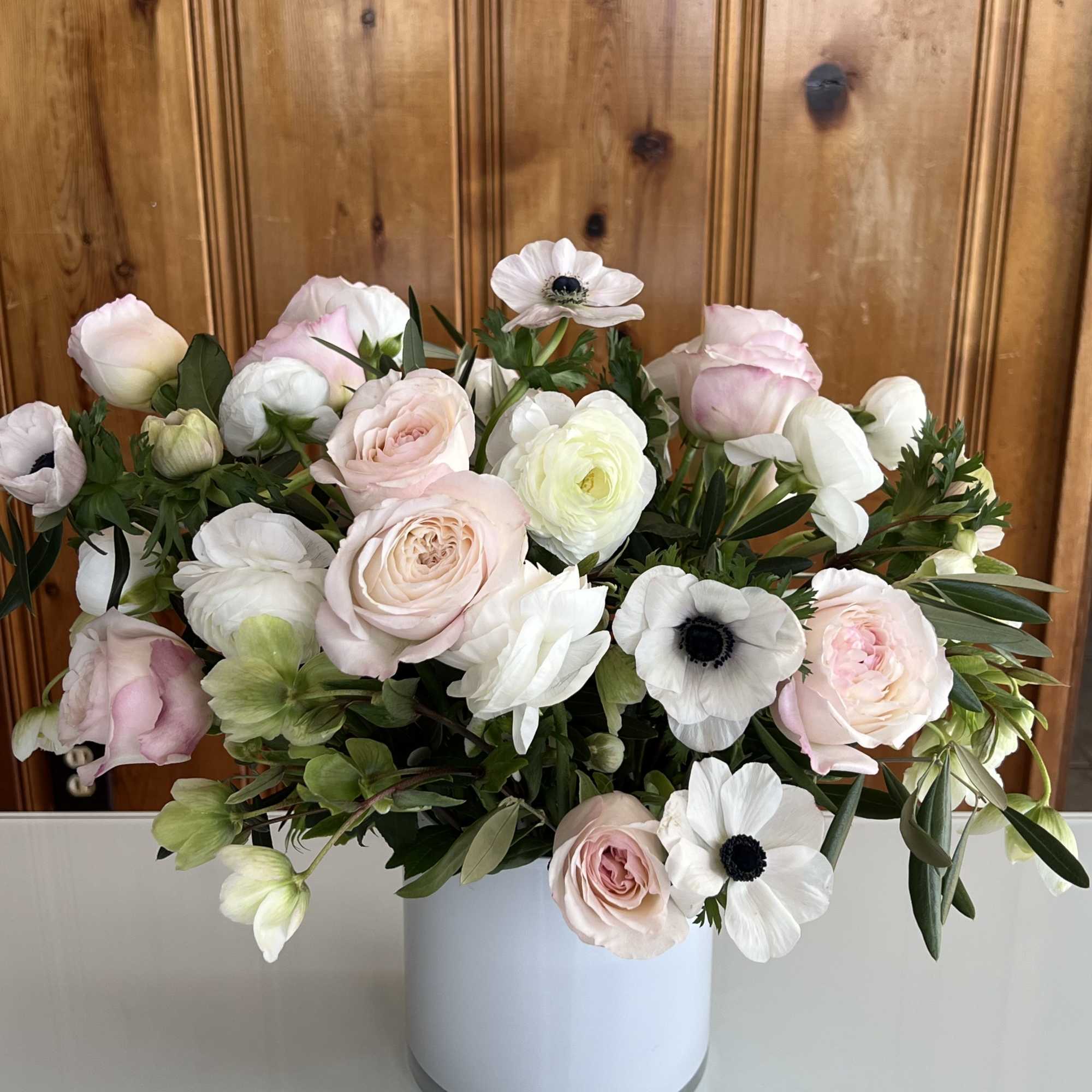 Blush and white flowers arranged in a white cylindrical vase