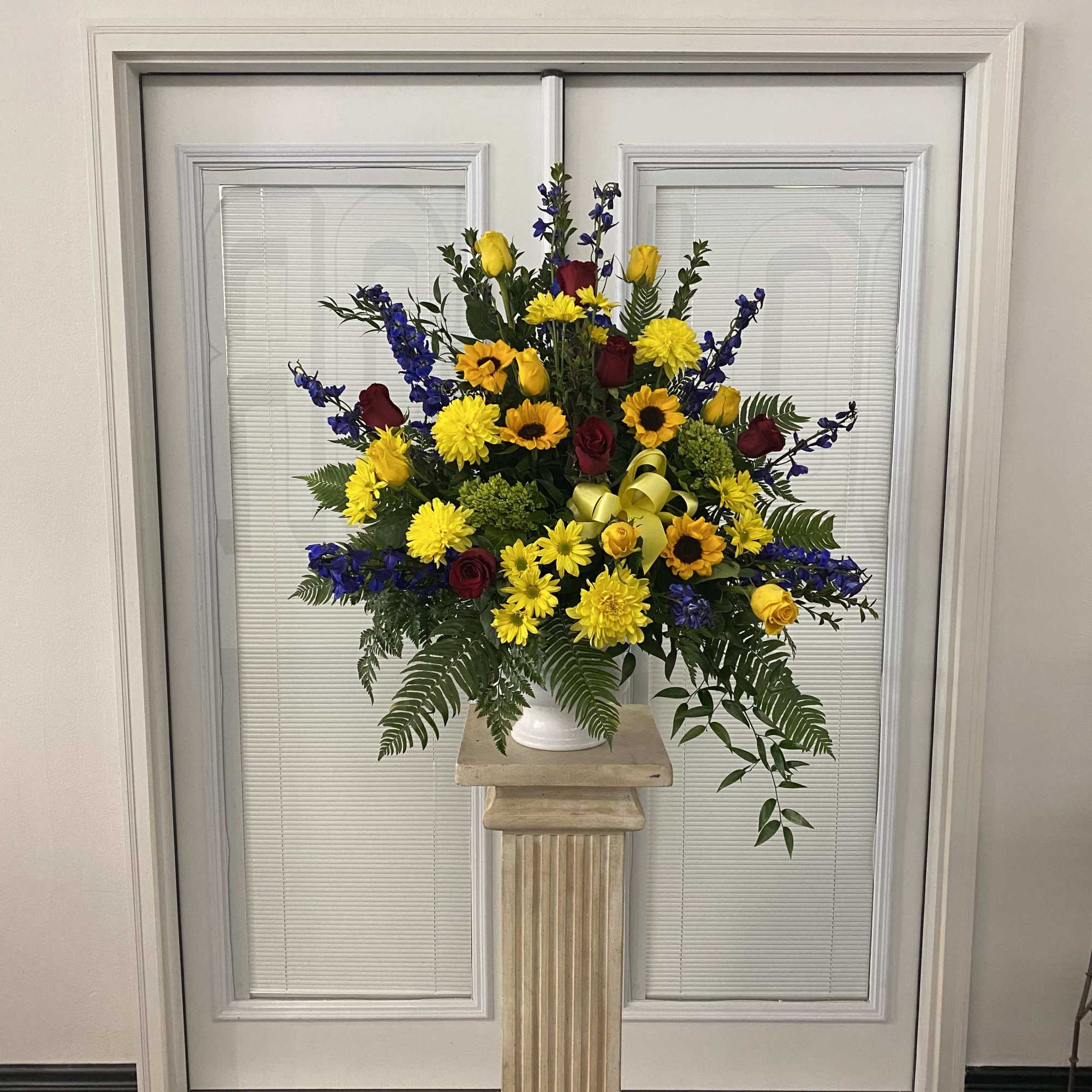 Large mixed flower arrangement in a white vase on a pedestal