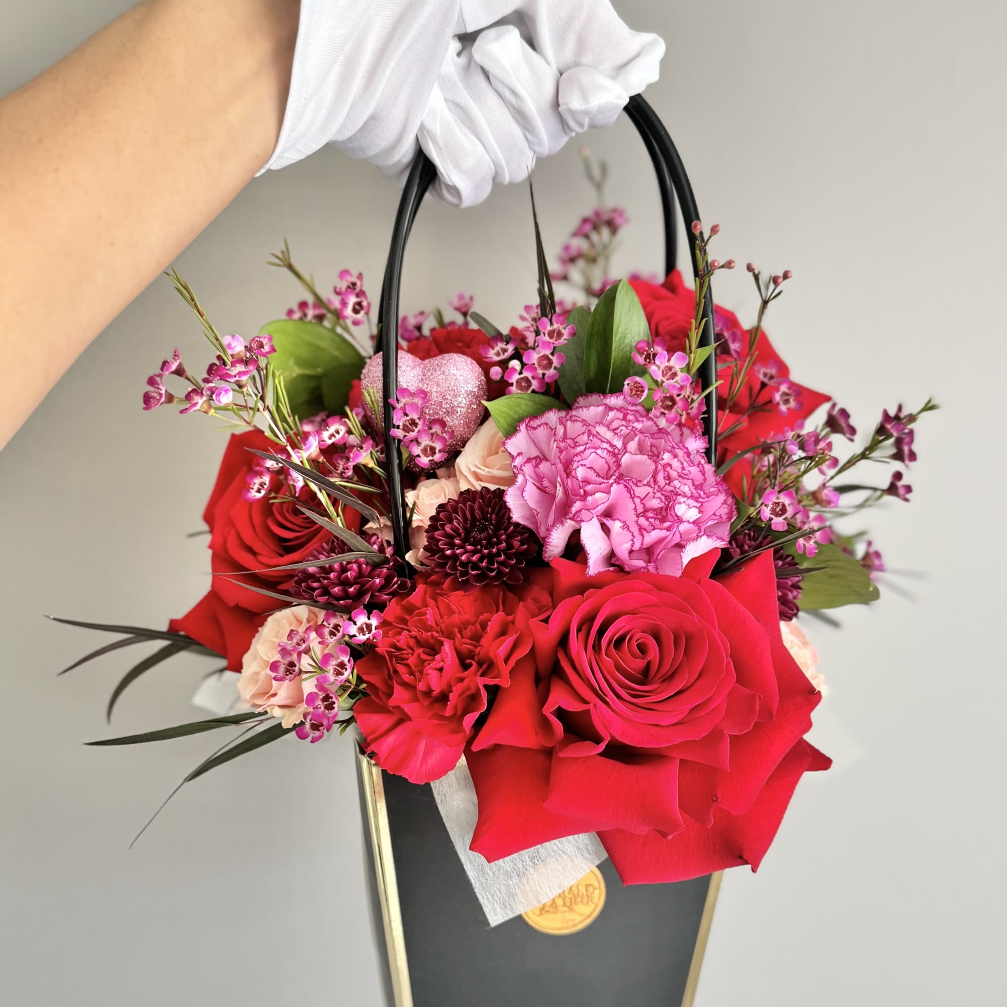 Handheld floral gift bag with red and pink roses and carnations