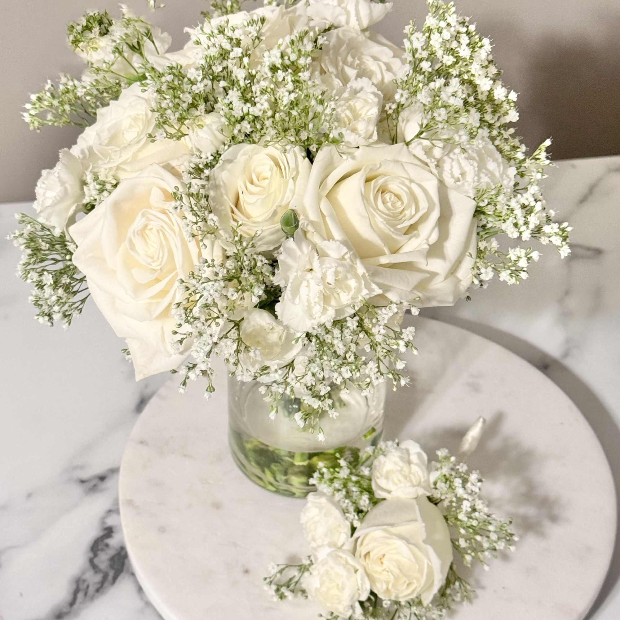 White rose bouquet in a clear glass vase with baby's breath