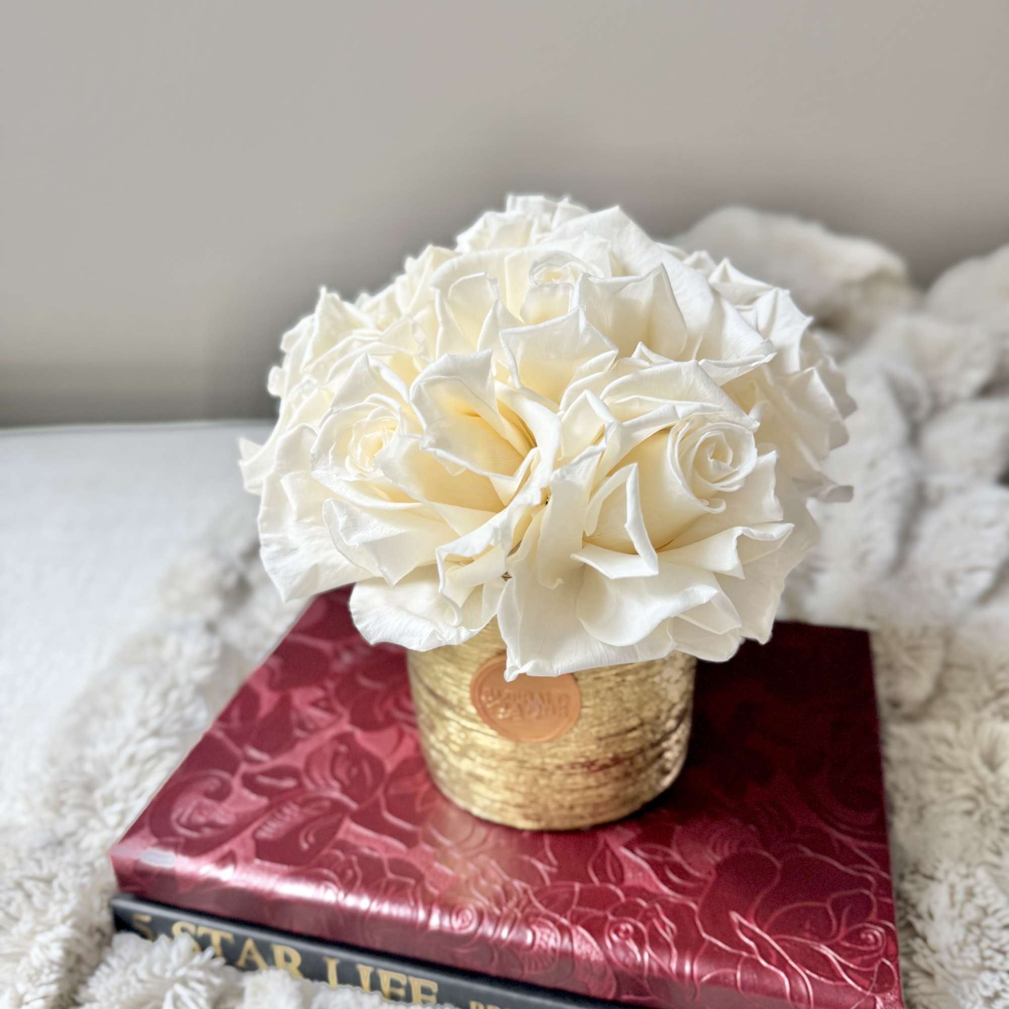 White rose bouquet in a gold container on stacked books