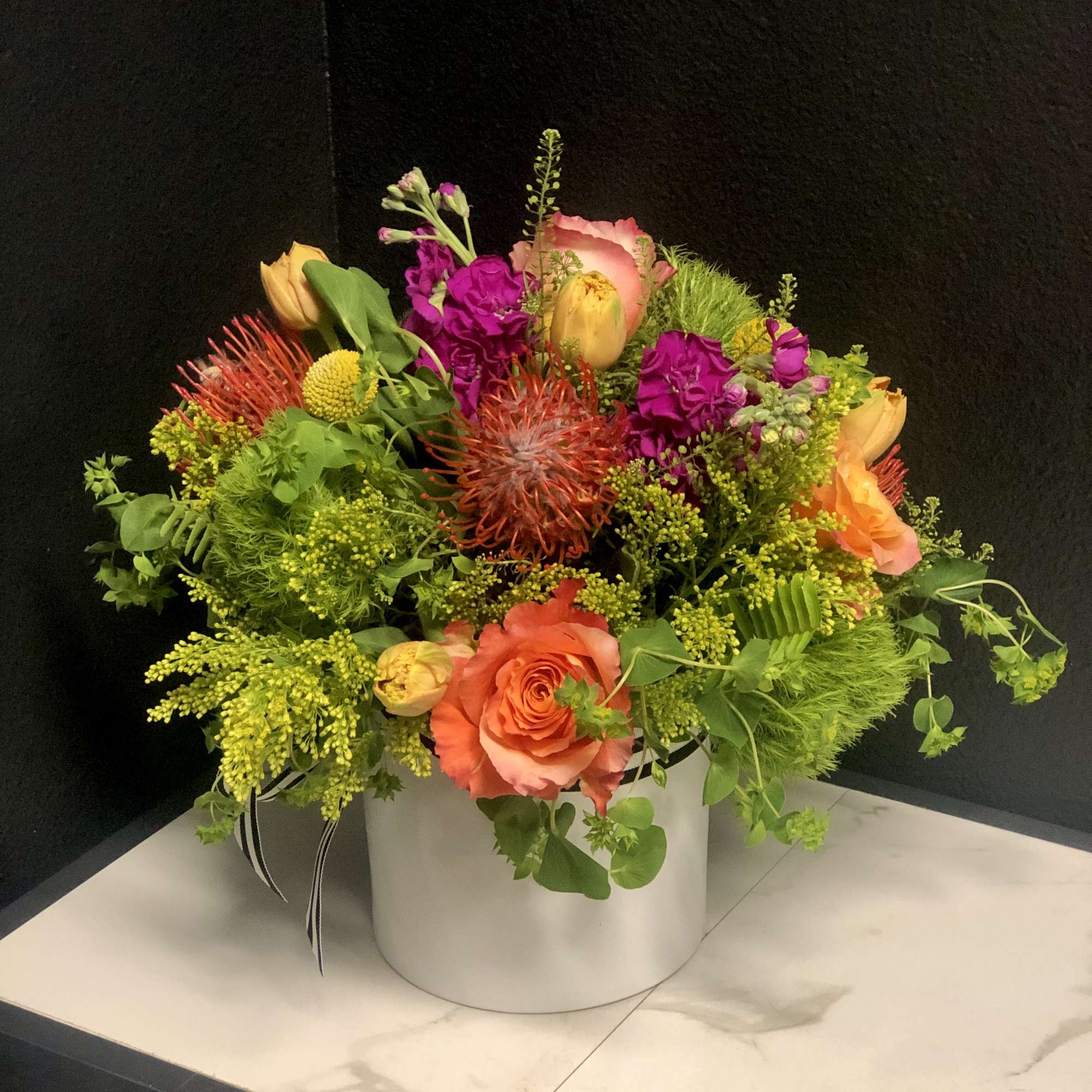 Bright mixed flower arrangement in a white round box