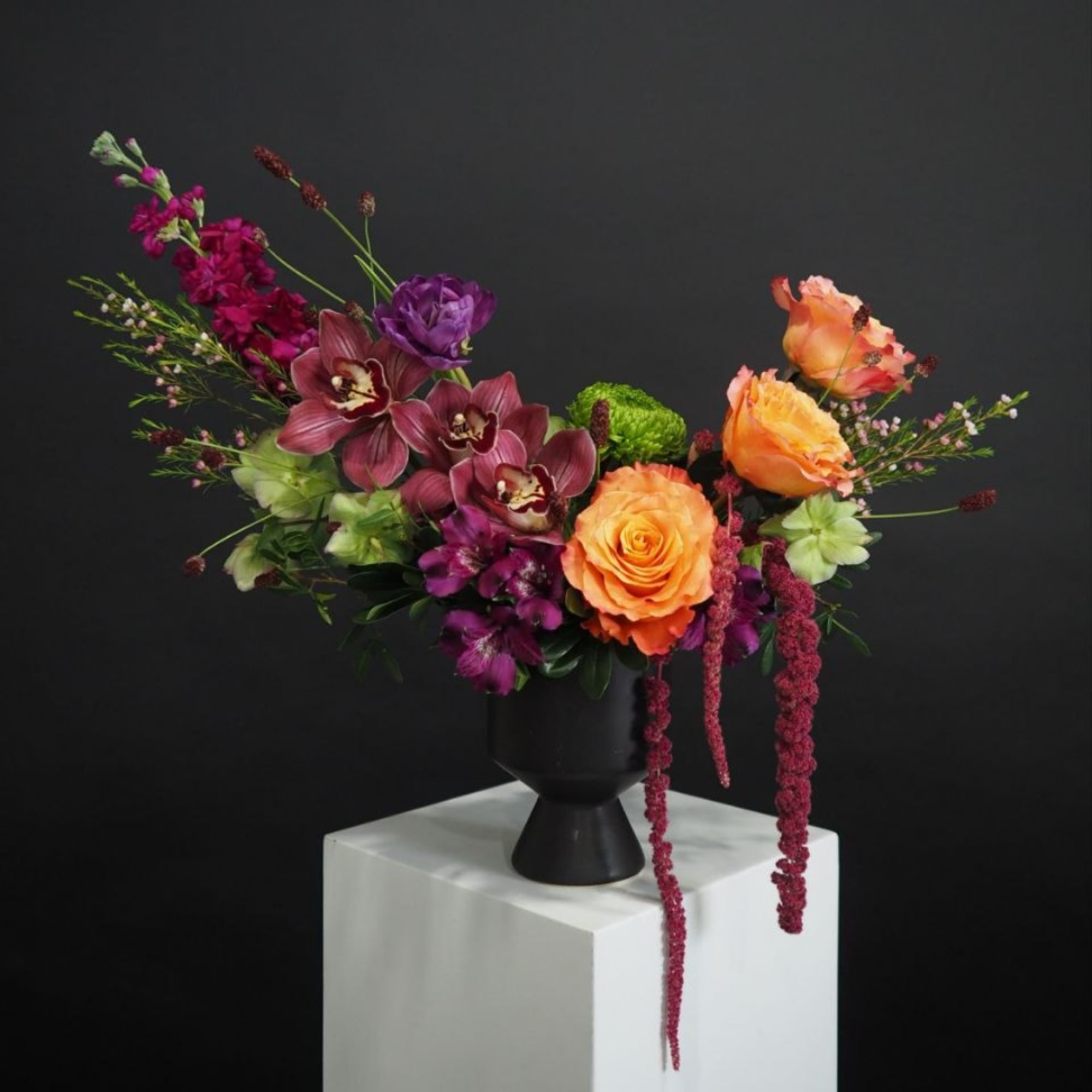 Colorful floral arrangement in a black vase on a white pedestal