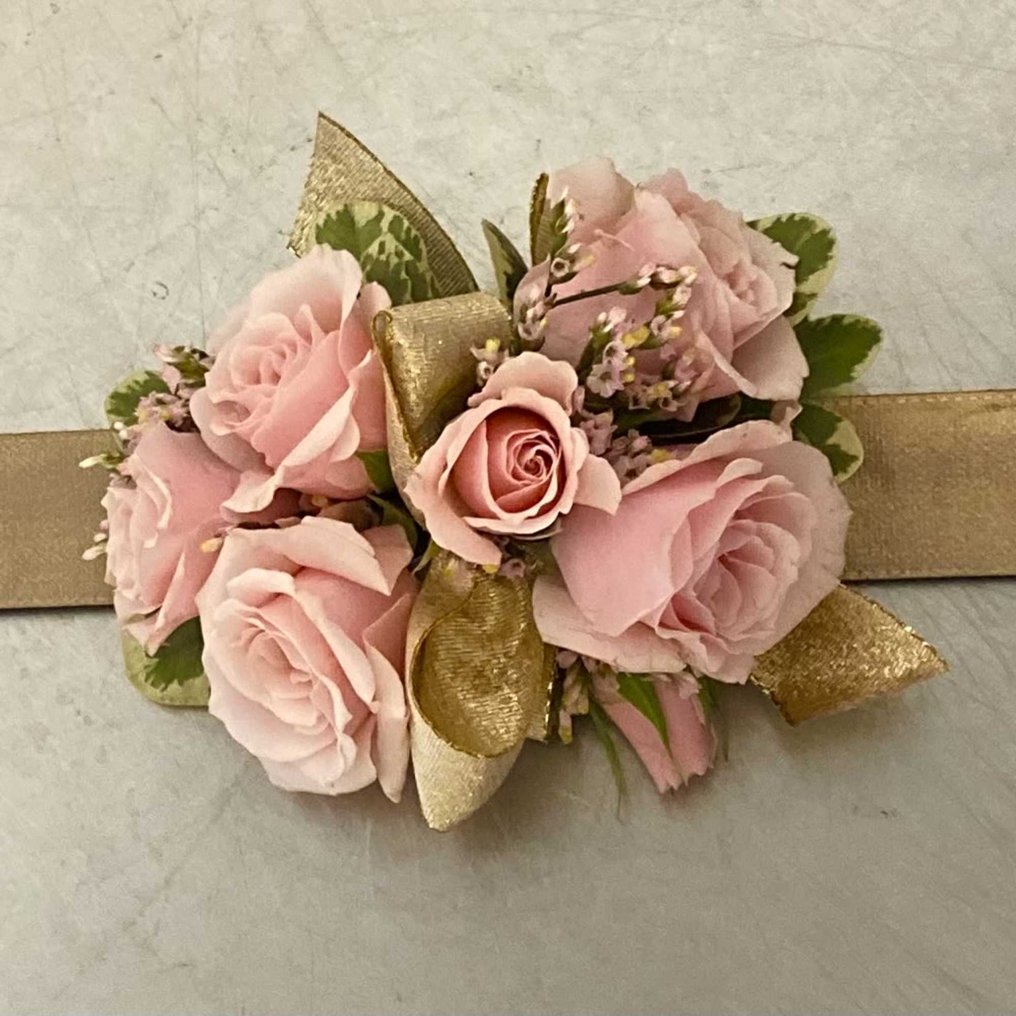 Pink rose corsage with gold ribbon on a wristband