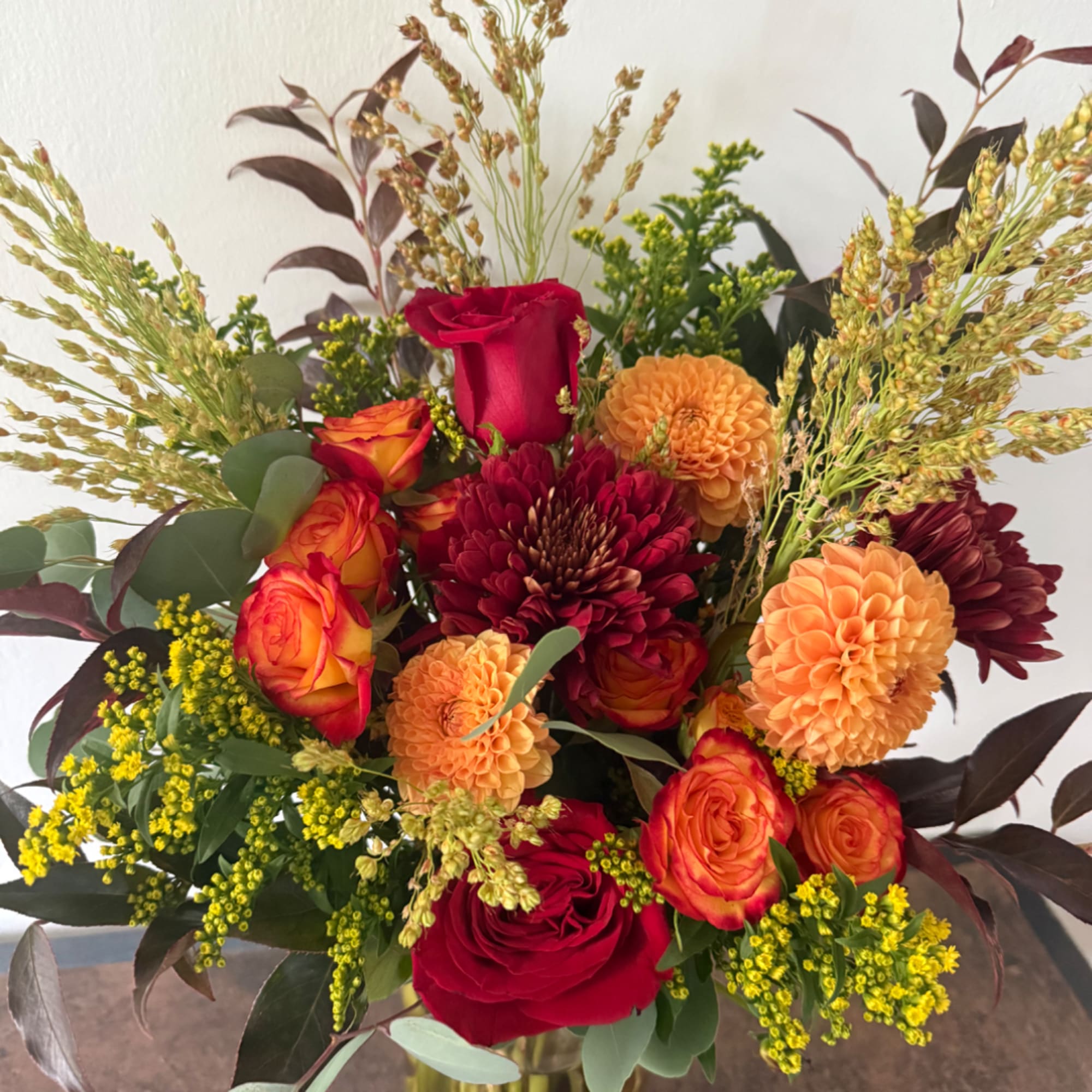 Mixed bouquet of red and orange roses with burgundy and peach blooms