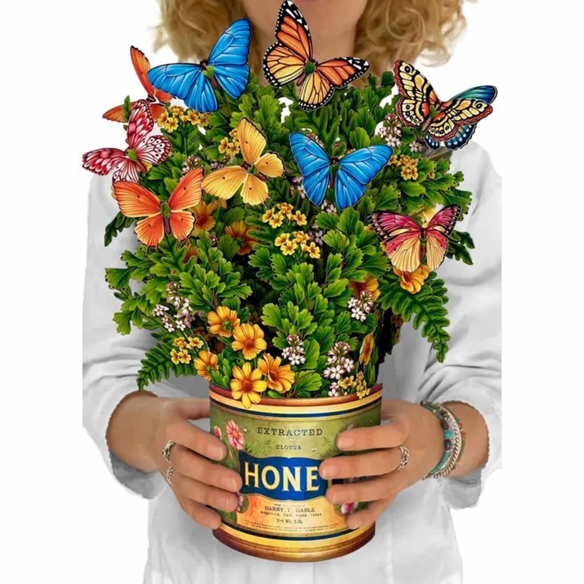 Person holding a honey can filled with colorful flowers and butterflies