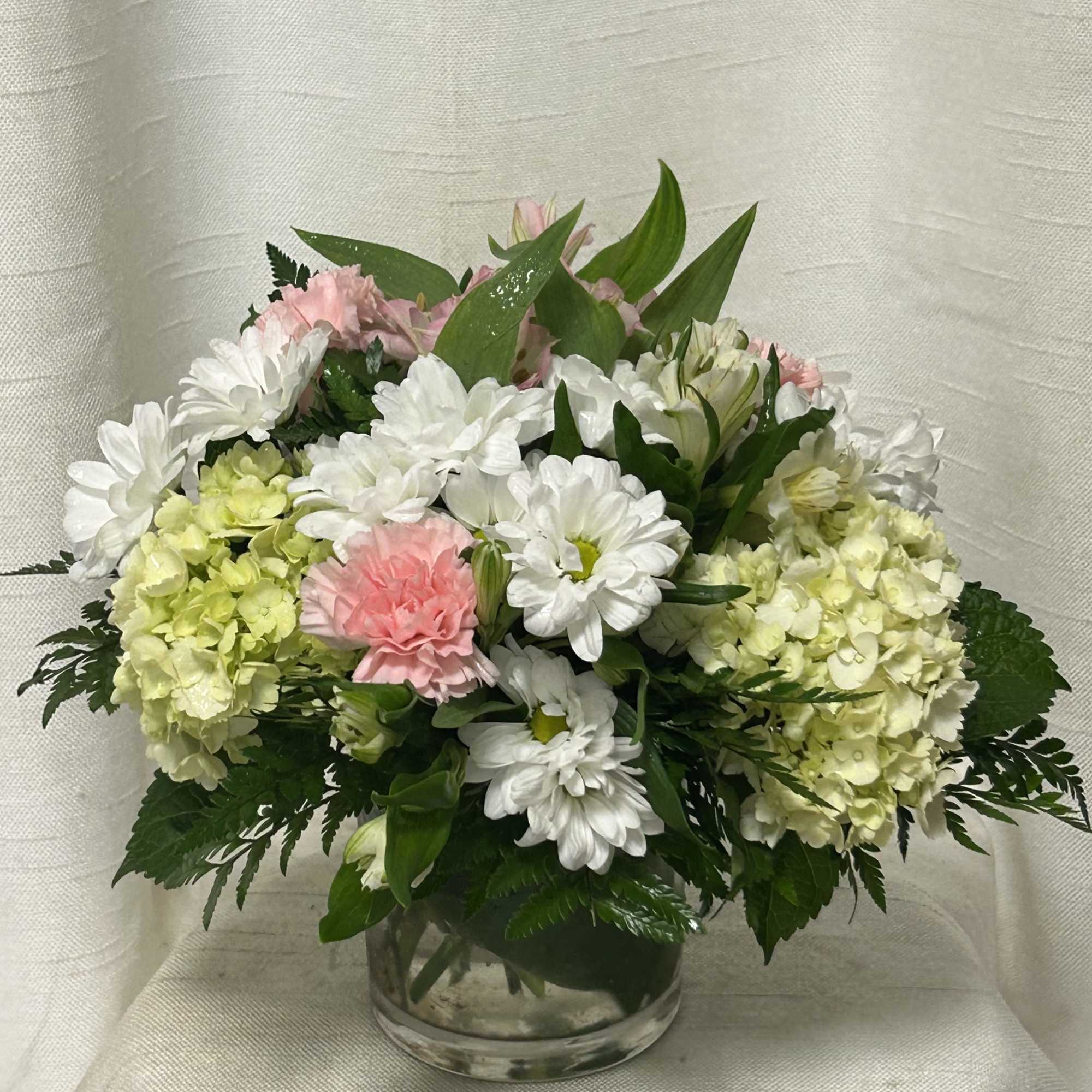 Pink and white flowers arranged in a clear glass vase