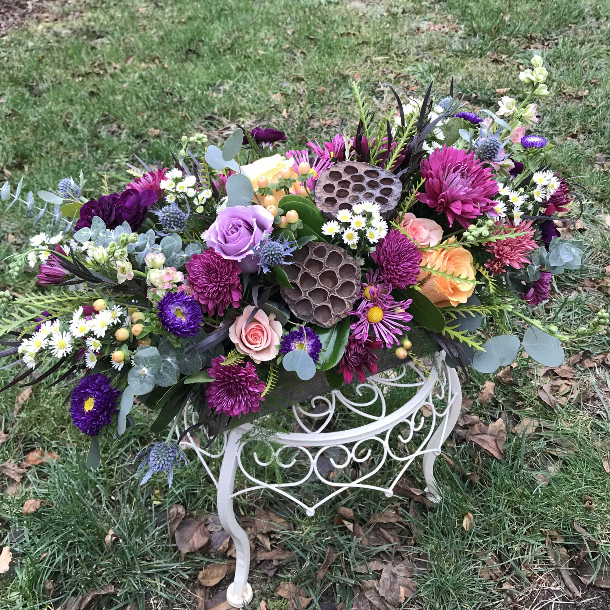 A lush centerpiece full of berries, lotus pods, seasonal foliage and fresh, photo 2 of 3