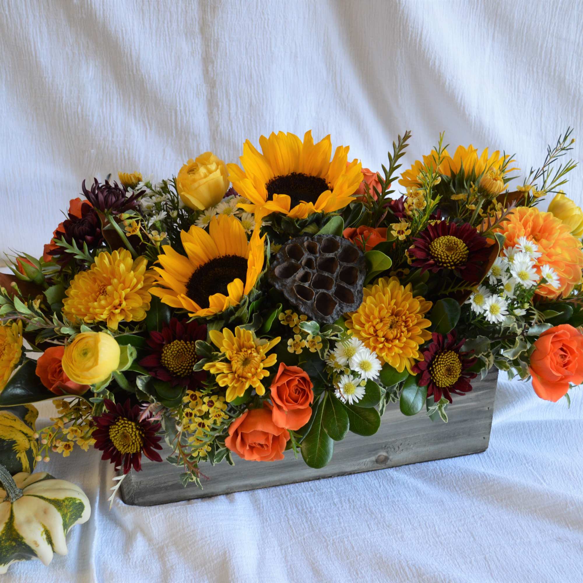 A lush centerpiece full of berries, lotus pods, seasonal foliage and fresh