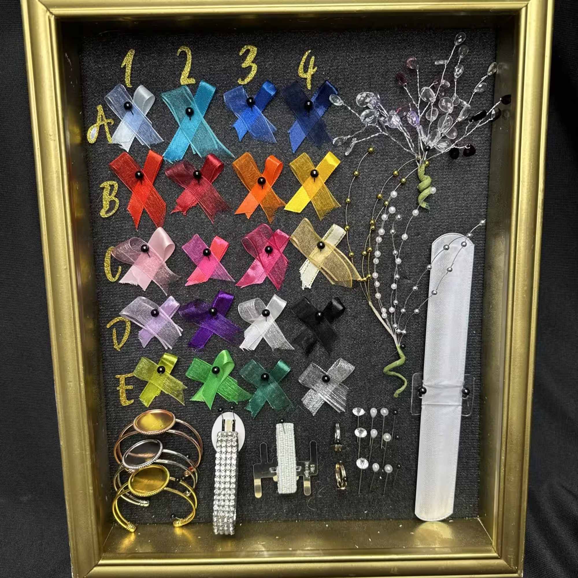 Framed display of colorful ribbon pins and bracelets on a black background