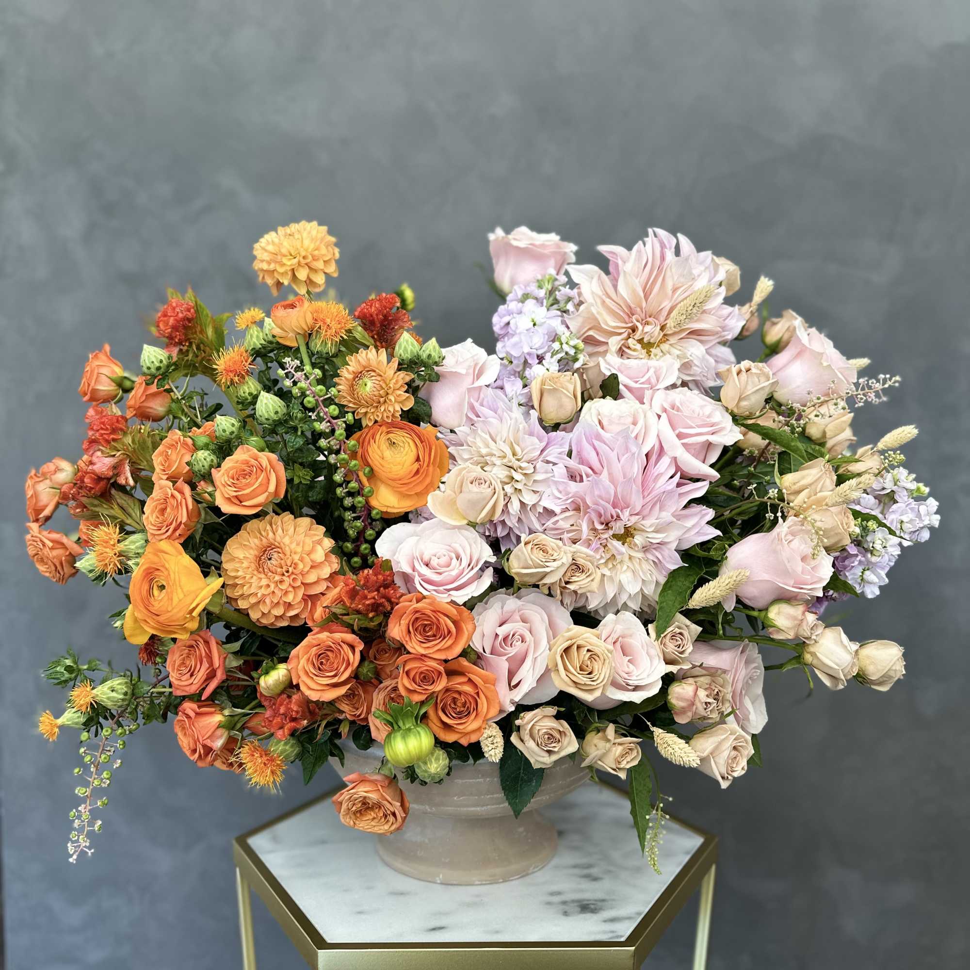 Mixed bouquet of orange, pink, and cream flowers in a ceramic vase