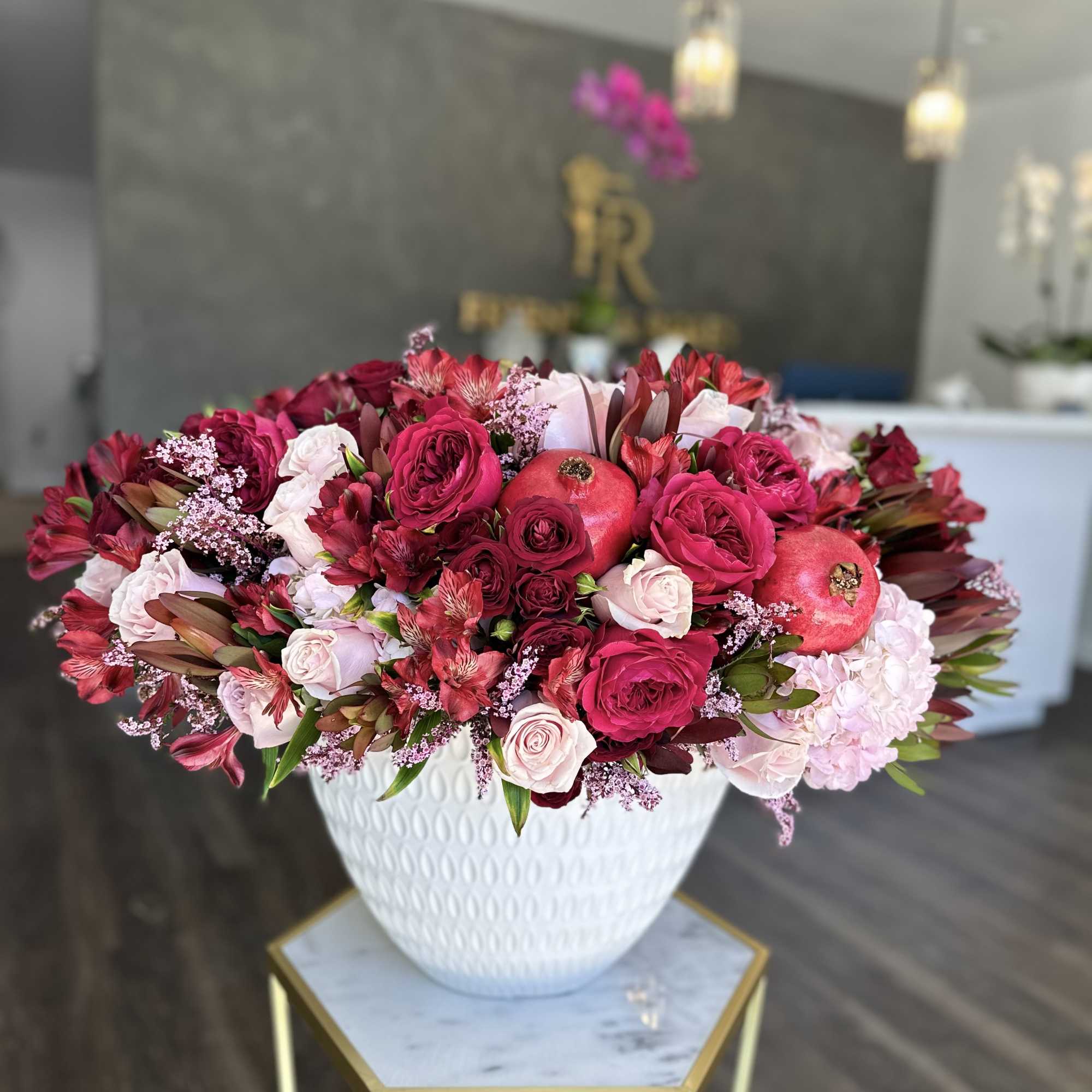 Large pink and red floral arrangement in a white vase
